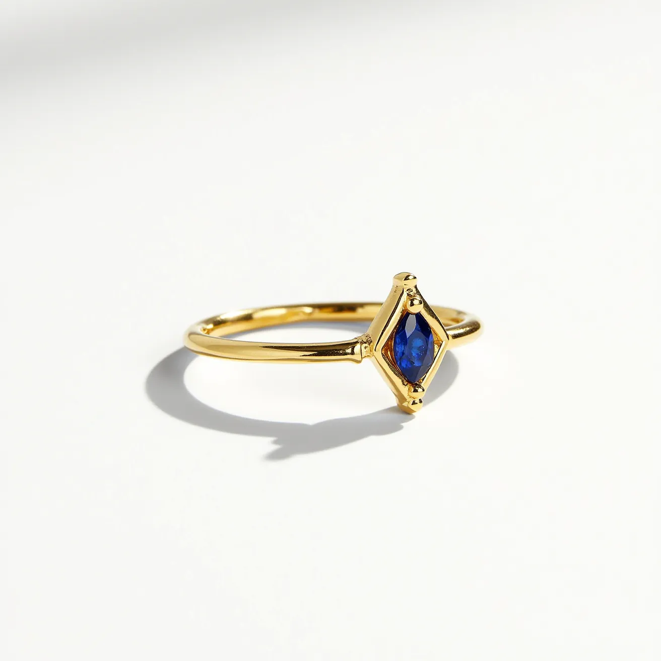 This fidget ring features a slender gold band that elegantly supports a vibrant blue stone at its center. The stone is a marquise cut, set within a diamond-shaped bezel setting that complements its faceted design. The gold band and setting provide a warm contrast to the cool hue of the blue stone, enhancing its brilliance. The minimalistic design allows for easy movement of the central element, making it both a stylish accessory and a functional fidget ring.