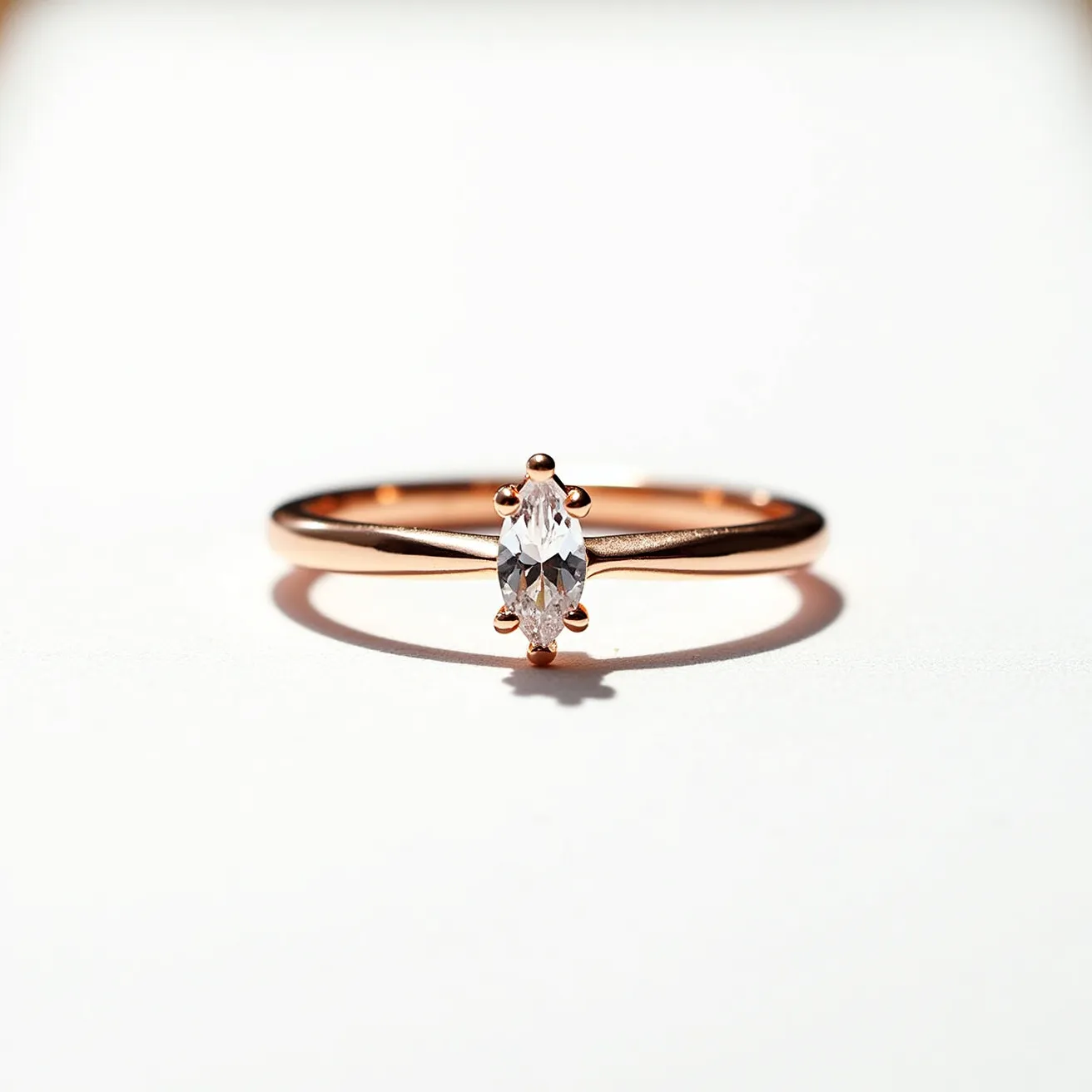 This fidget ring features a sleek design crafted from what appears to be rose gold, giving it a warm, elegant tone. It is adorned with a marquise-cut clear gem, possibly a diamond or a cubic zirconia, positioned at its center. The gem is securely held in place by a six-prong setting, enhancing its brilliance and adding structural integrity. The simplicity and minimalist styling of the ring underscore its beauty while offering functionality for fidgeting.