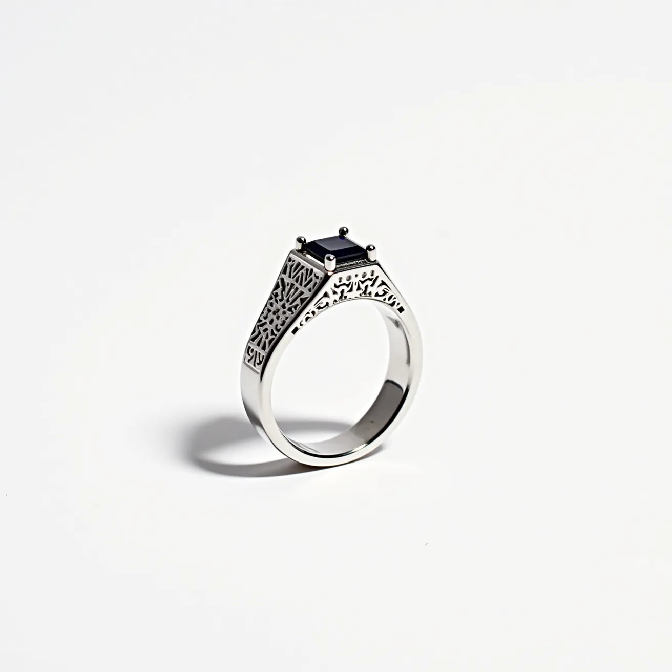 This fidget ring features a sleek metal band, likely made from stainless steel or a similar alloy, exhibiting intricate etched patterns along its sides. It boasts a square cut, dark gem—possibly an onyx or black cubic zirconia—securely set in a prong setting at the top, which allows for subtle movement when touched. The design emphasizes both aesthetics and the tactile satisfaction characteristic of fidget rings, without any additional clasps or attachments, making it both functional and stylish for everyday wear.