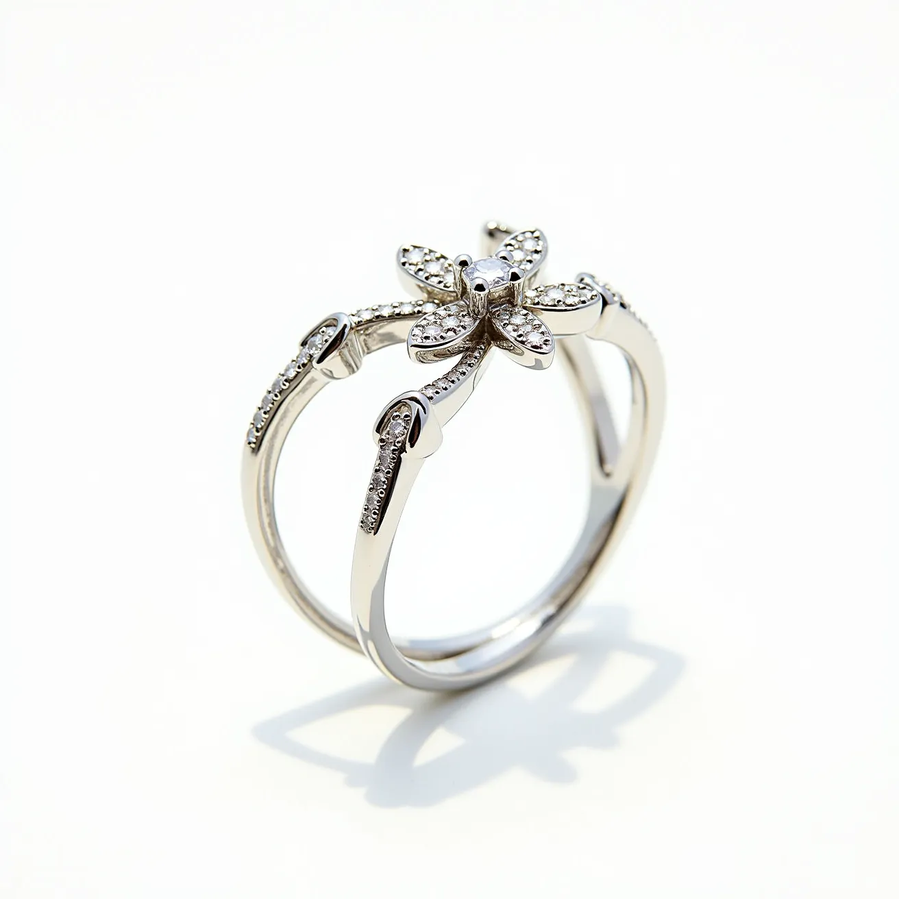 This floral ring features a delicate design with a flower motif at its center, crafted from a polished metal, likely silver or white gold. The petals are adorned with small round-cut diamonds, enhancing the ring's elegance and sparkle. These stones are pavé set, providing a shimmering effect across the flower's surface. The band is split into two sleek, smooth lines that converge at the base, adding a modern twist to the classic floral theme. The absence of an external clasp or attachment speaks to its seamless circular form.