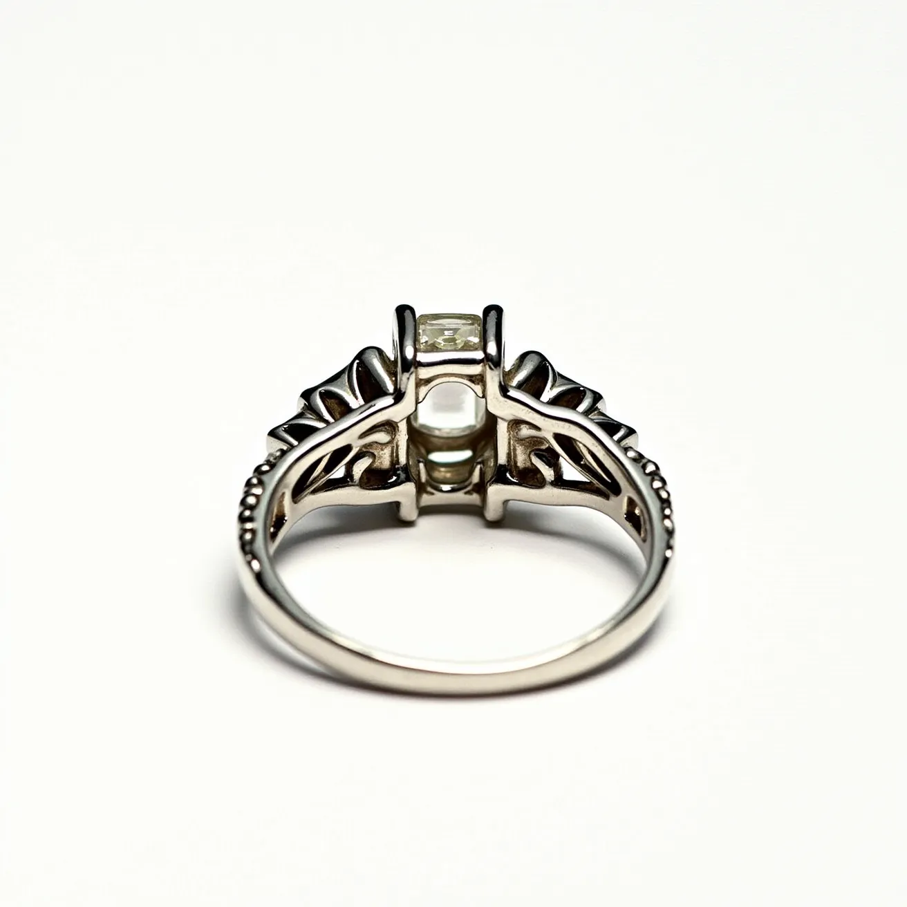 This floral ring features an intricate design crafted from a silver-toned metal. At its center, the ring showcases a clear gemstone, likely a diamond, set in a distinctive, raised bezel setting that accentuates its brilliance. The band is adorned with floral motifs that extend to the sides, enhancing the organic elegance of the piece. The metalwork includes intricate details that resemble leaves or petals, adding to the floral theme. The ring's craftsmanship and choice of materials suggest a delicate yet sophisticated piece, perfect for those who appreciate detailed artistry in jewelry.