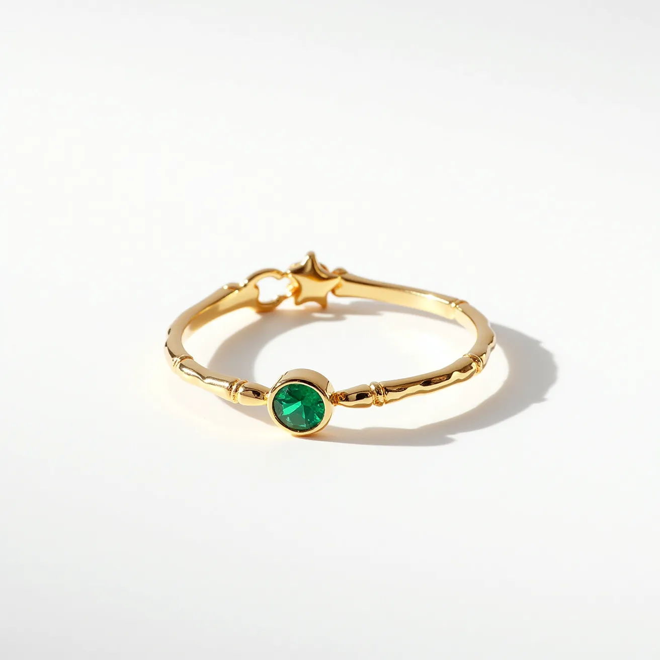 This friendship ring features a delicate gold band with a bamboo-like texture that adds to its charm. At its center, there is a round-cut green gemstone securely set in a bezel setting, which beautifully highlights its vibrant color. The ring also includes a star-shaped charm, adding a playful and unique touch. The overall design is elegant and symbolic, making it a perfect piece to celebrate friendship.