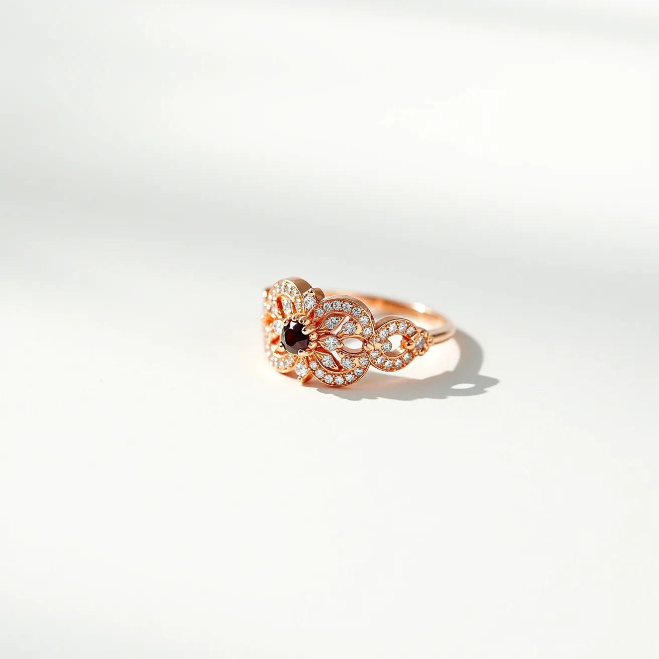 This garnet ring showcases a beautifully intricate design featuring a central round-cut garnet set in a delicate rose gold band. The garnet is surrounded by an ornate filigree pattern adorned with numerous small, sparkling white stones, likely diamonds or high-quality cubic zirconia, that accentuate the centerpiece. The ring's setting highlights the garnet's rich red hue, enhancing its visual appeal. The openwork design adds an elegant and airy feel to the piece, making it a stunning accessory for formal occasions.