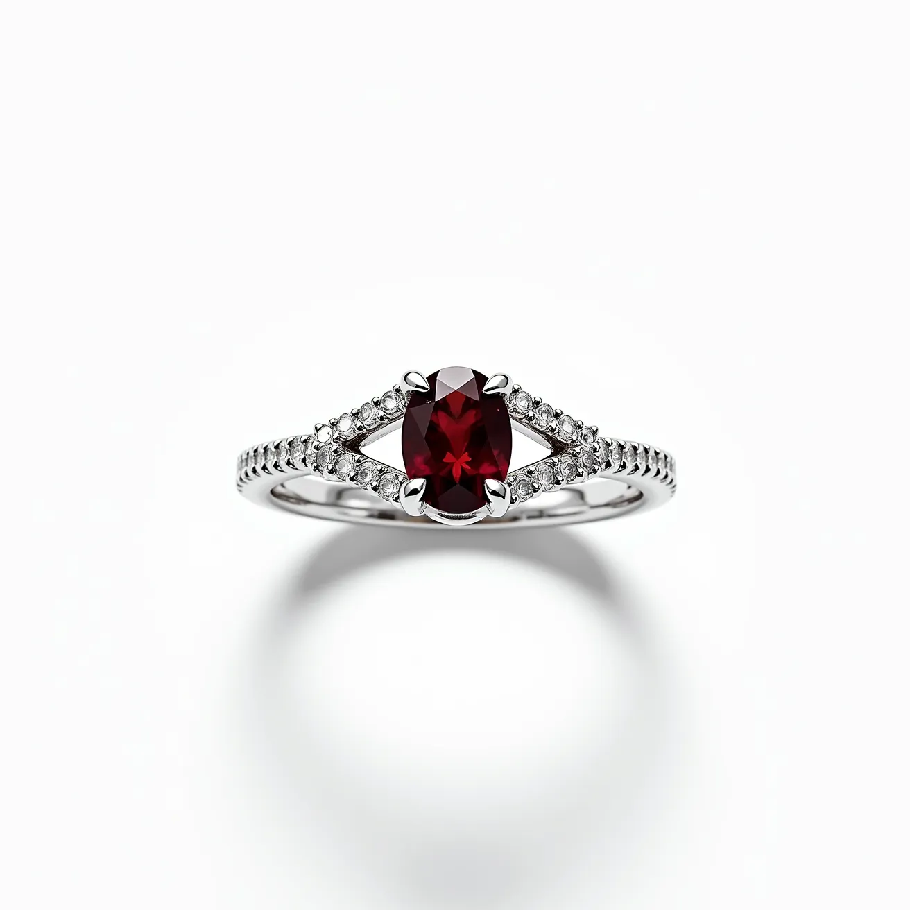 This garnet wedding ring features a striking oval-cut garnet at its center, set within a sleek metal band likely made of white gold or platinum. The garnet is secured by four prongs, enhancing its deep red hue. Flanking the central stone, a series of small round brilliant-cut diamonds are pave-set into the band, adding a delicate sparkle that complements the boldness of the garnet. The classic combination of garnet and diamonds is beautifully accentuated by the refined metal setting, making this a timeless and elegant piece.