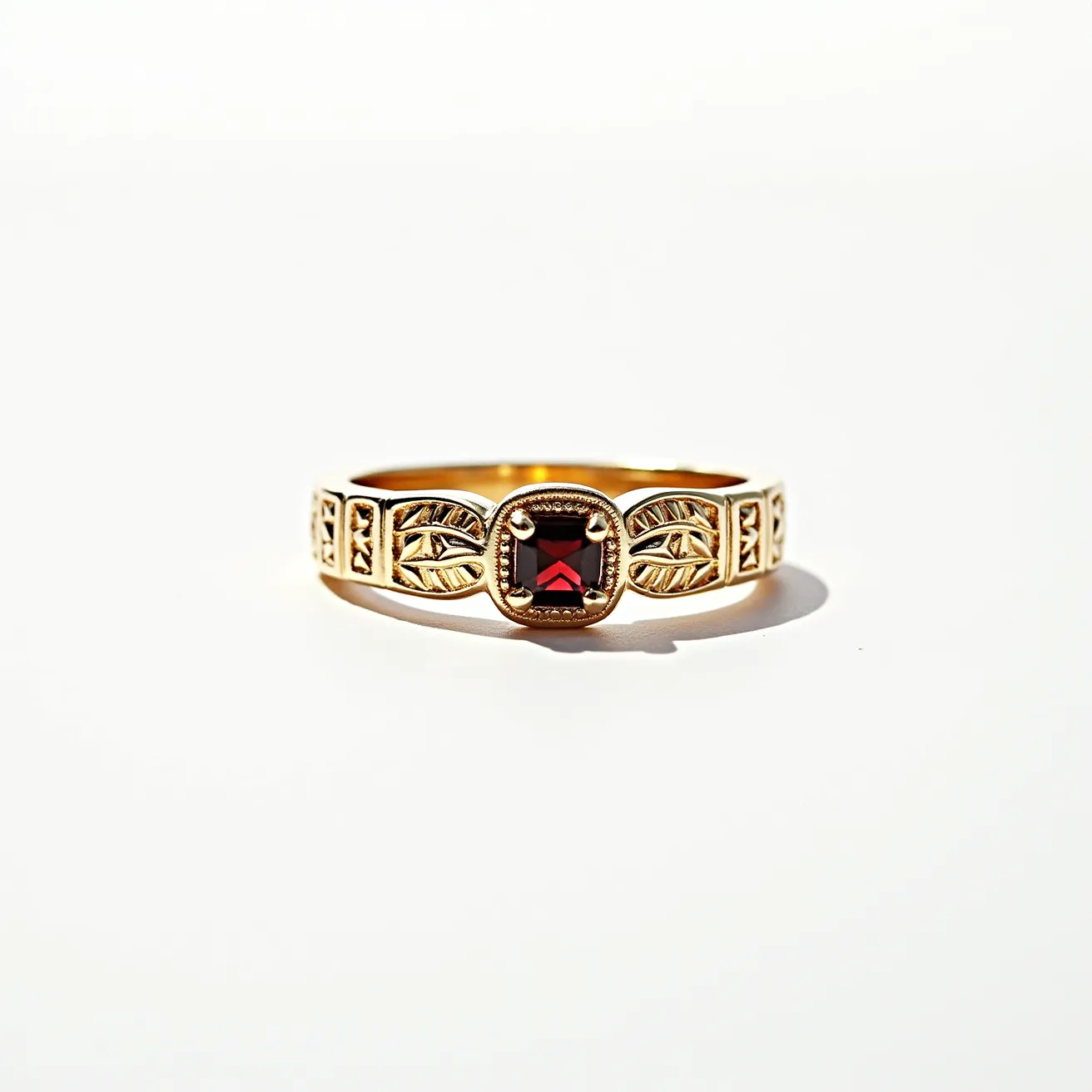 This garnet wedding ring showcases a captivating square-cut garnet, imbued with a deep red hue, which is set at the center. The garnet is secured in a bezel setting, framed by intricate metalwork that resembles leaf patterns, adding a touch of elegance to the overall design. The band appears to be crafted from a gold material, enhancing the richness of the garnet. The delicate detailing along the band complements the central stone, creating a harmonious balance between the gem and the metal. This ring embodies a blend of classic and artistic elements, making it a striking piece.