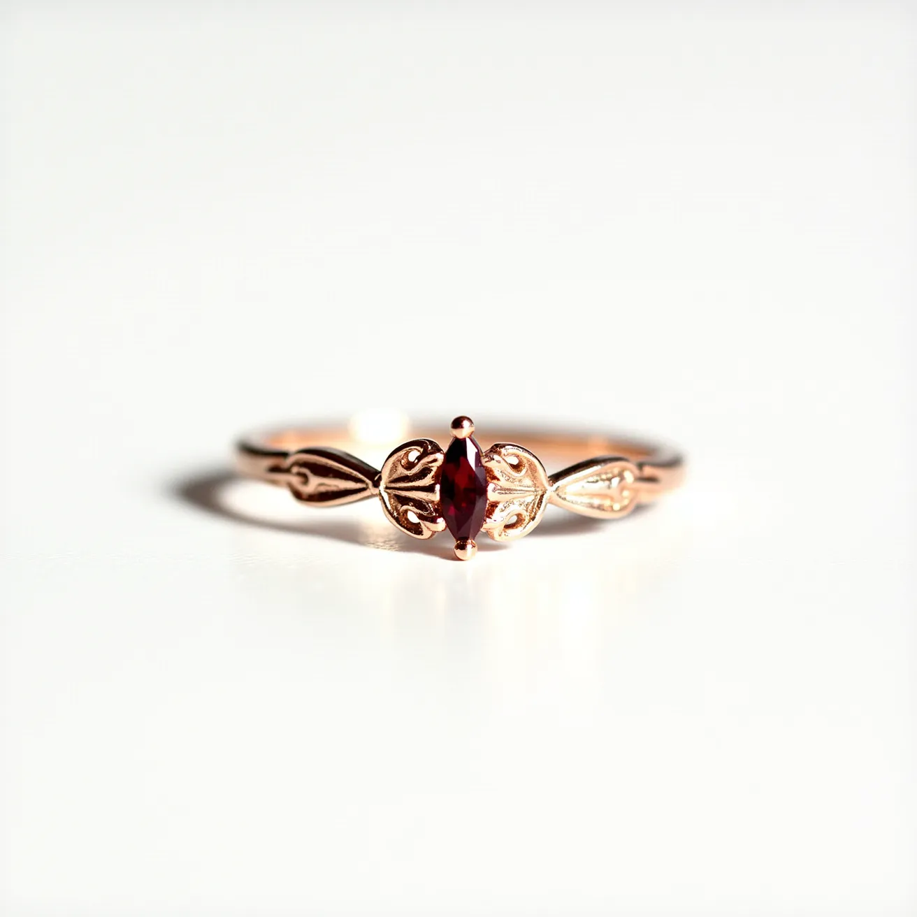 This garnet wedding ring features a marquise-cut garnet as its centerpiece, set securely within a prong setting. The band is crafted from rose gold, showcasing an intricate design with leaf-like motifs that enhance its elegance. The garnet's deep red hue contrasts beautifully with the warm tones of the rose gold band, creating a sophisticated and timeless aesthetic. The craftsmanship highlights a delicate balance between the gemstone and the artistic design of the metalwork, making it a unique and stylish choice for a wedding ring.