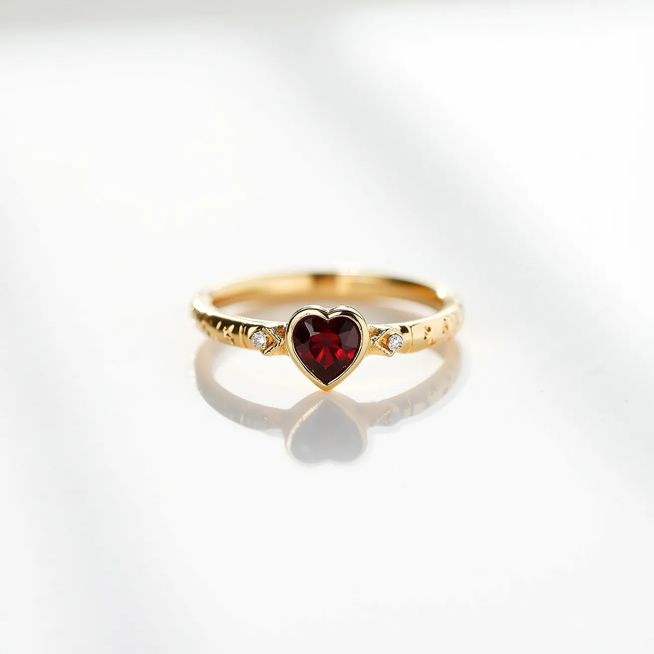 This garnet wedding ring features a striking heart-shaped garnet as its centerpiece, showcasing a vibrant red hue. The garnet is set in a bezel setting, offering a smooth and secure presentation. Flanking the central stone are two small round diamonds, each set in prong settings that add a touch of sparkle and elegance. The band appears to be made of gold, adding a warm and classic look to the piece. The design of this ring combines romantic symbolism with timeless craftsmanship, making it a cherished keepsake.