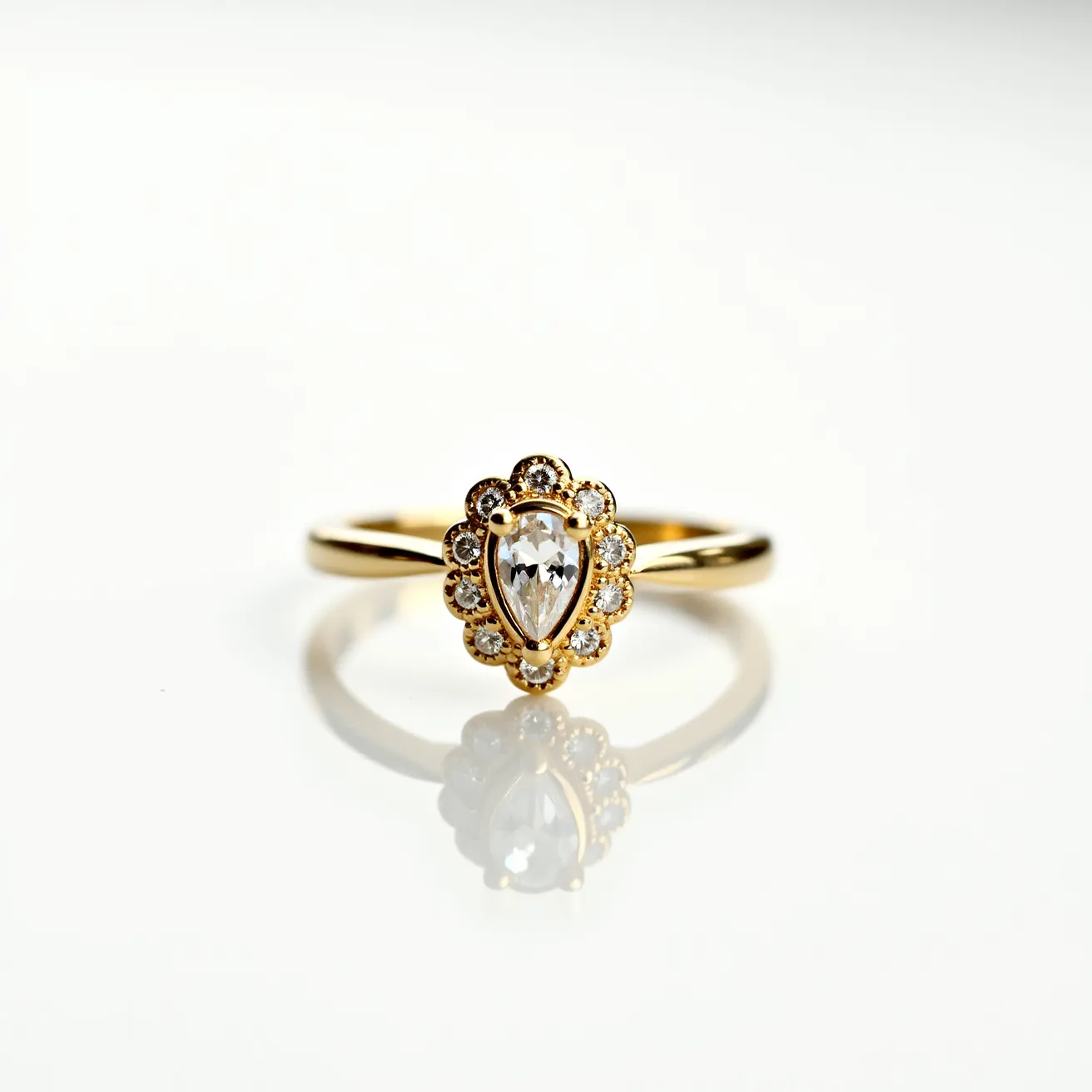 This gemstone engagement ring features a pear-shaped center stone set in a bezel setting, accentuated by a halo of smaller round stones. The ring is crafted from yellow gold, providing a classic and elegant appearance. The smaller stones surrounding the central gem enhance its brilliance and are likely secured in prong settings, complementing the overall design. The band is smooth and polished, contributing to a sophisticated and timeless aesthetic.