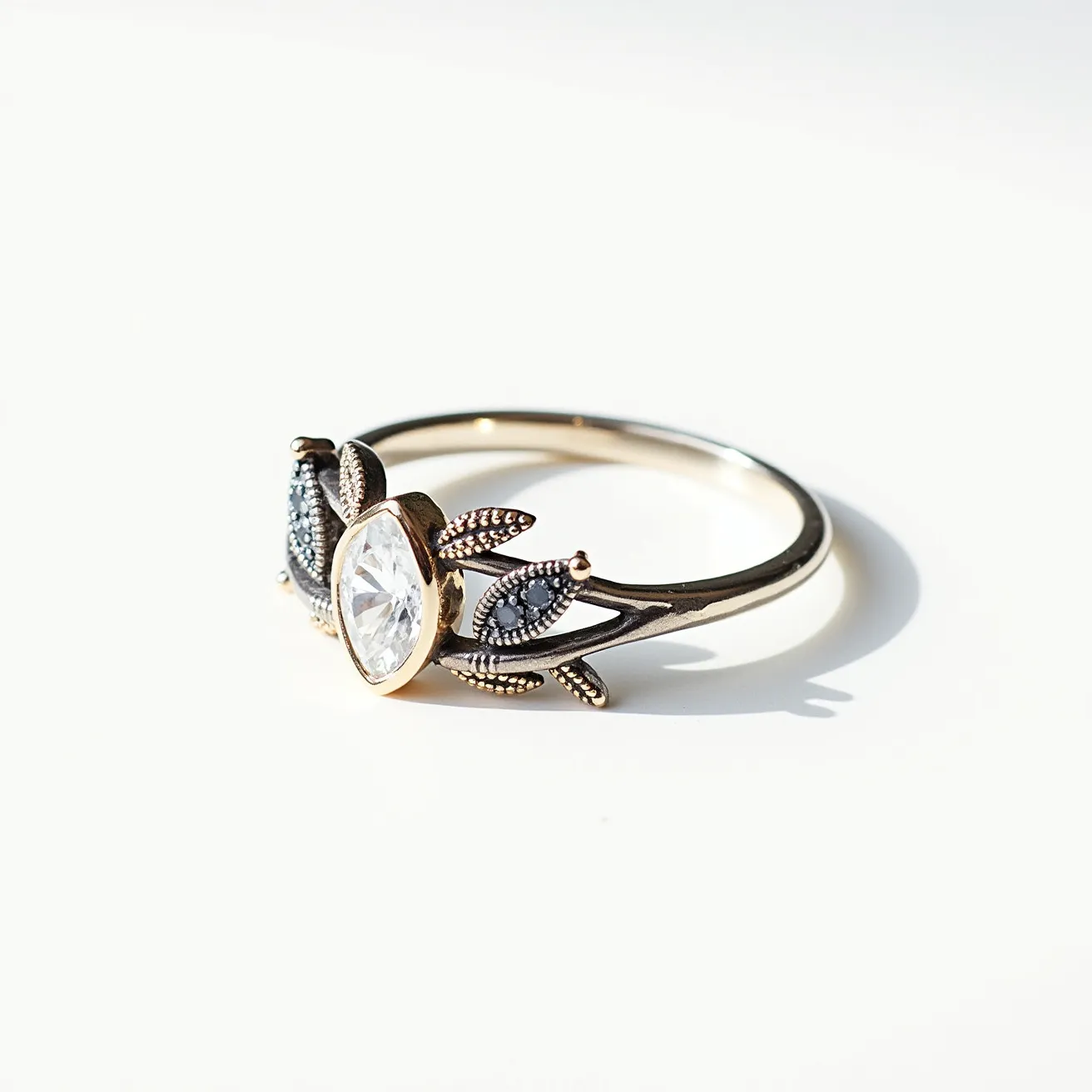 This gemstone ring features a striking central stone cut in a marquise shape, set in a bezel setting, which enhances its elegance and security. The band appears to be crafted from a yellow gold or gold-toned material that complements the central stone. The design includes intricate metalwork resembling leaves or branches alongside the main stone, embellished with smaller stones or textured metalwork, adding depth and detail to the overall design. The ring has a smooth, continuous band that completes its sophisticated aesthetic.