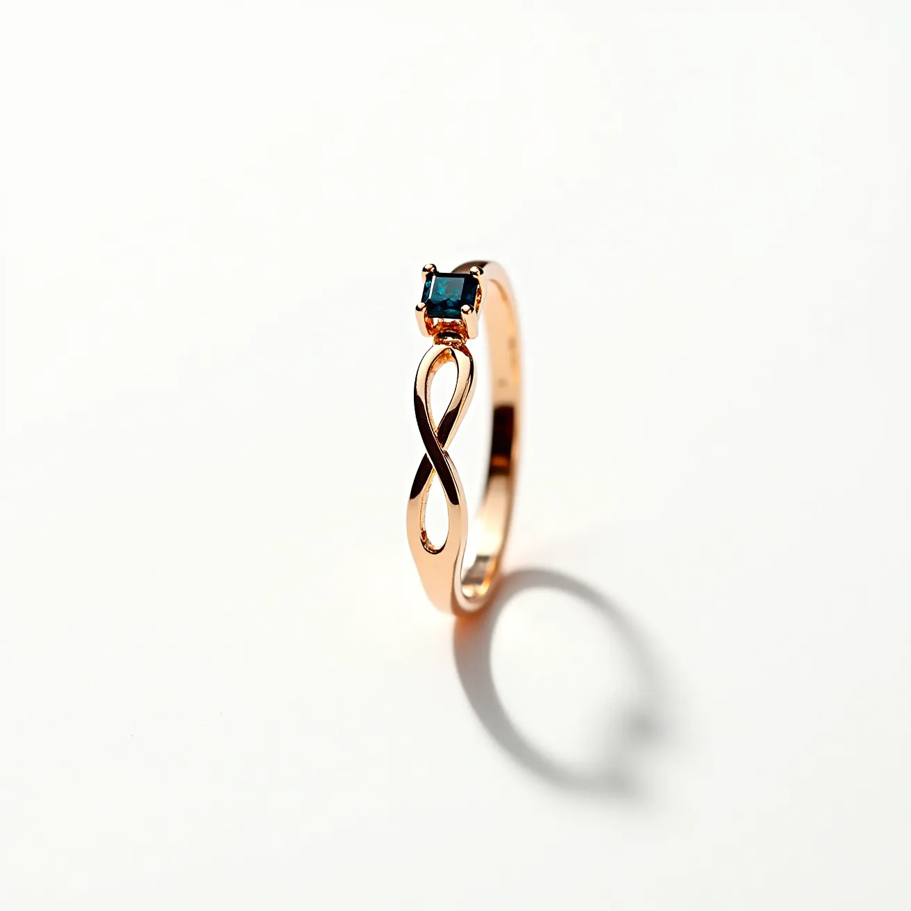 This gold thumb ring features a sleek and elegant design crafted from polished gold, forming a smooth band with an infinity symbol accent. It is adorned with a single blue gemstone, which is cut in a square shape and set into a four-prong setting, providing a secure hold while allowing light to enhance the stone's natural sparkle. The overall design is both simple and sophisticated, highlighting the beauty of both the gold and gemstone with no additional clasps or attachments.