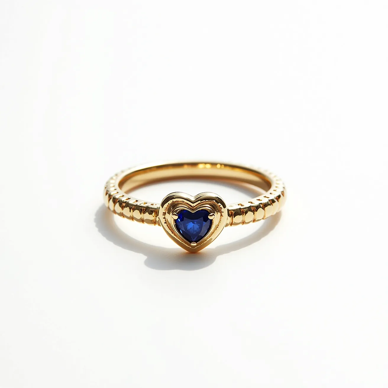 This gold wedding band features a meticulously crafted band that showcases a pattern of alternating textures, adding a tactile elegance to its design. At its center, a heart-shaped blue sapphire is beautifully set, offering a striking contrast with its vibrant color against the warm golden hue of the band. The sapphire is securely held within a heart-shaped bezel setting, which enhances its prominence and provides a secure enclosure without detracting from its brilliance. The overall design of the band and the gemstone interplay to create a harmonious and romantic piece that conveys a sense of timeless love and commitment.