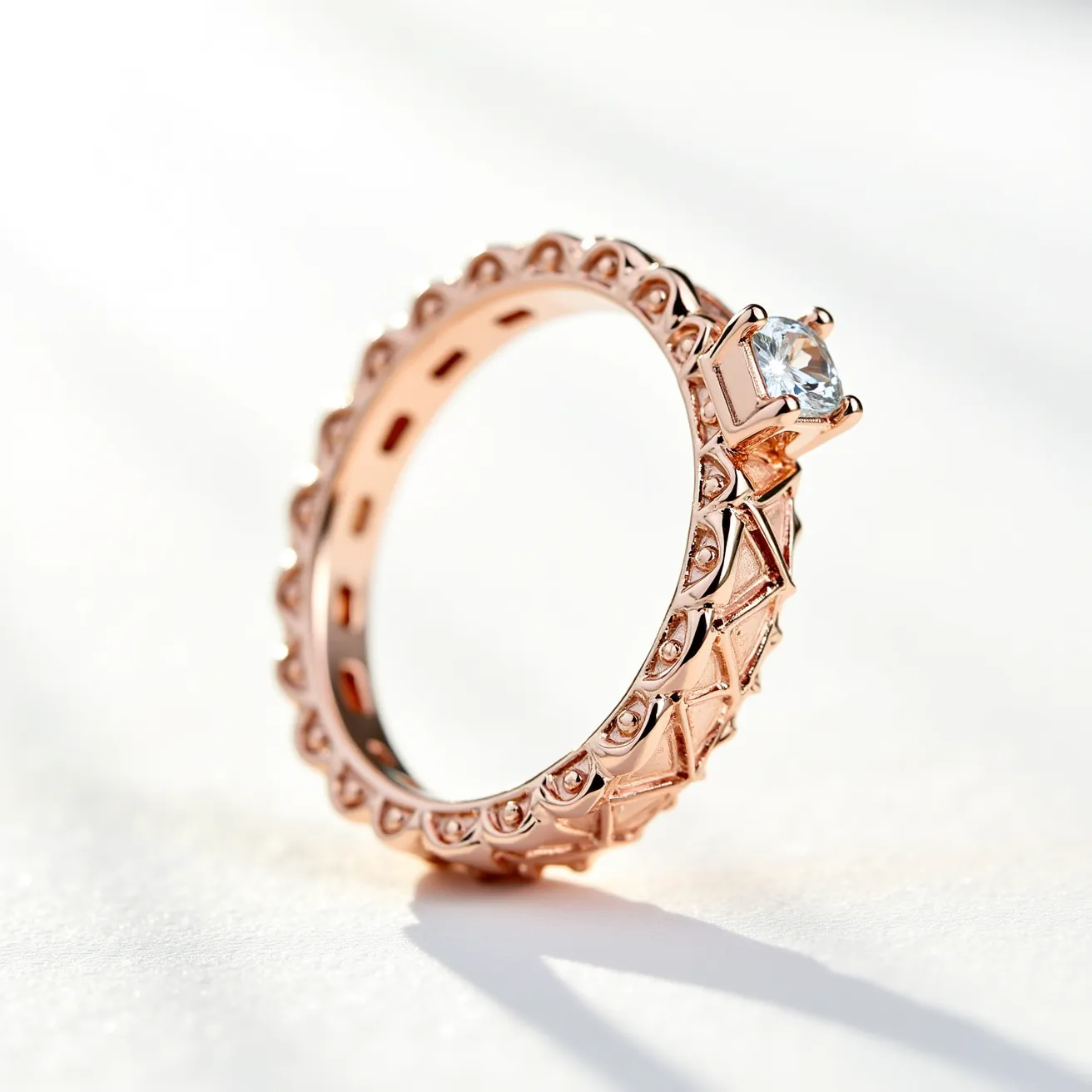 This gold wedding band features an intricate design with a series of raised patterns encircling the band, crafted from rose gold. A prominent feature is the solitaire round-cut diamond set in a prong setting, which elevates the gem above the band, allowing maximum light exposure and enhancing its brilliance. The band does not include any additional clasps or attachments, maintaining a seamless circular form. The craftsmanship of the band showcases detailed artistry, with the combination of rose gold and diamond providing a classic yet elegant appearance.