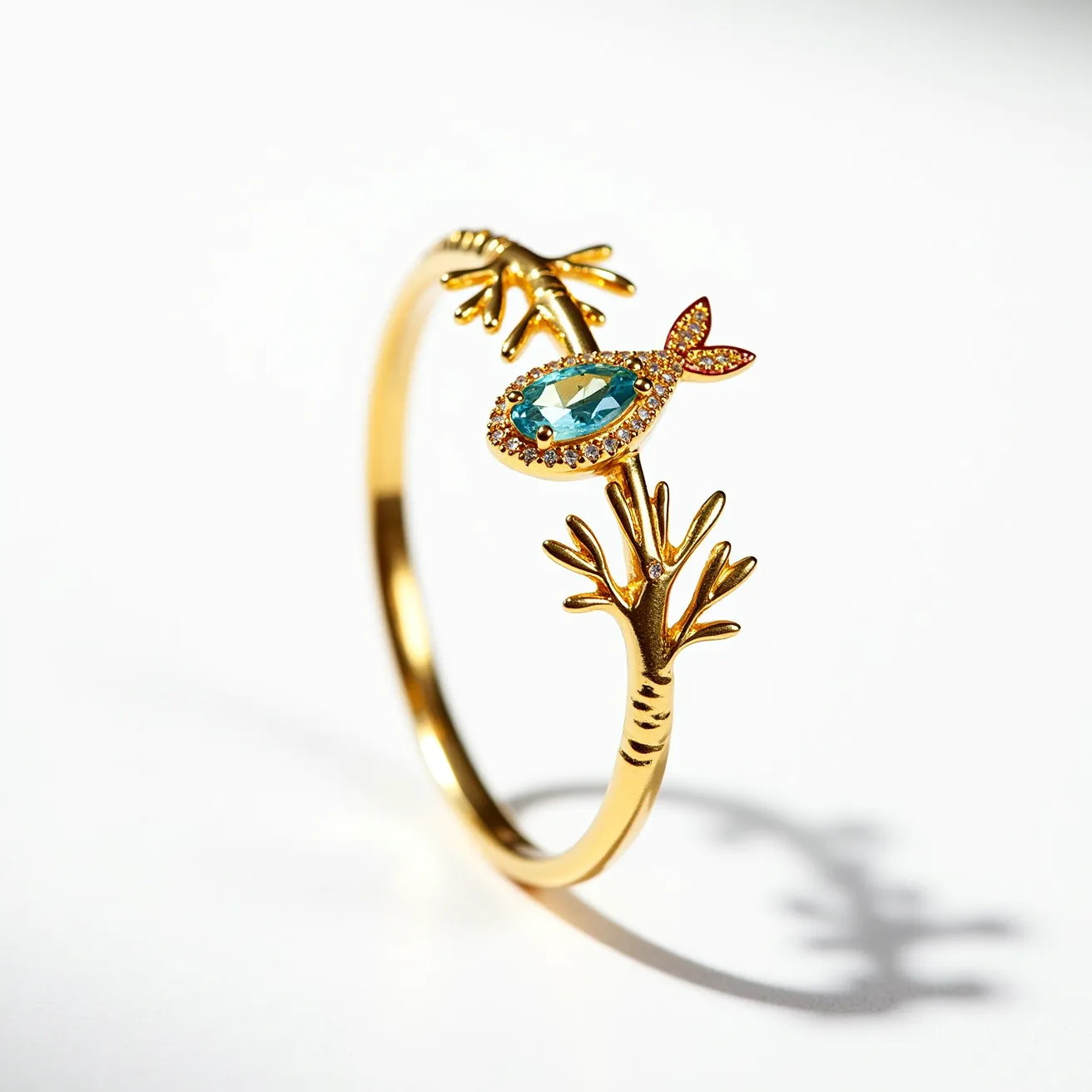 This golden bird ring features an intricate design resembling branches that form the band of the ring. Atop this band rests an oval cut blue gemstone, likely aquamarine, set in a bezel setting that resembles a bird. Surrounding the central gemstone is a delicate halo of smaller stones, which appear to be round-cut and add a touch of sparkle. The bird's tail and head, highlighted with tiny pink stones, are crafted with attention to detail, enhancing the overall whimsical theme. The ring itself is made primarily from polished gold, giving it a luxurious and elegant appearance.