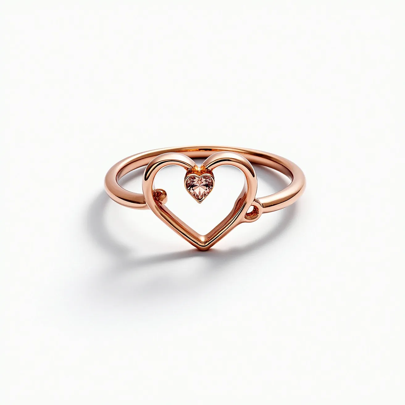 This heart promise ring features a polished rose gold band, elegantly crafted to form an open heart design. At its center is a heart-shaped gemstone, likely a pink diamond or similarly colored stone, securely held in a bezel setting that enhances its delicate brilliance. The combination of the rose gold metal and the soft, romantic hue of the gemstone gives the ring a warm and sophisticated appearance, ideal for symbolizing enduring affection.