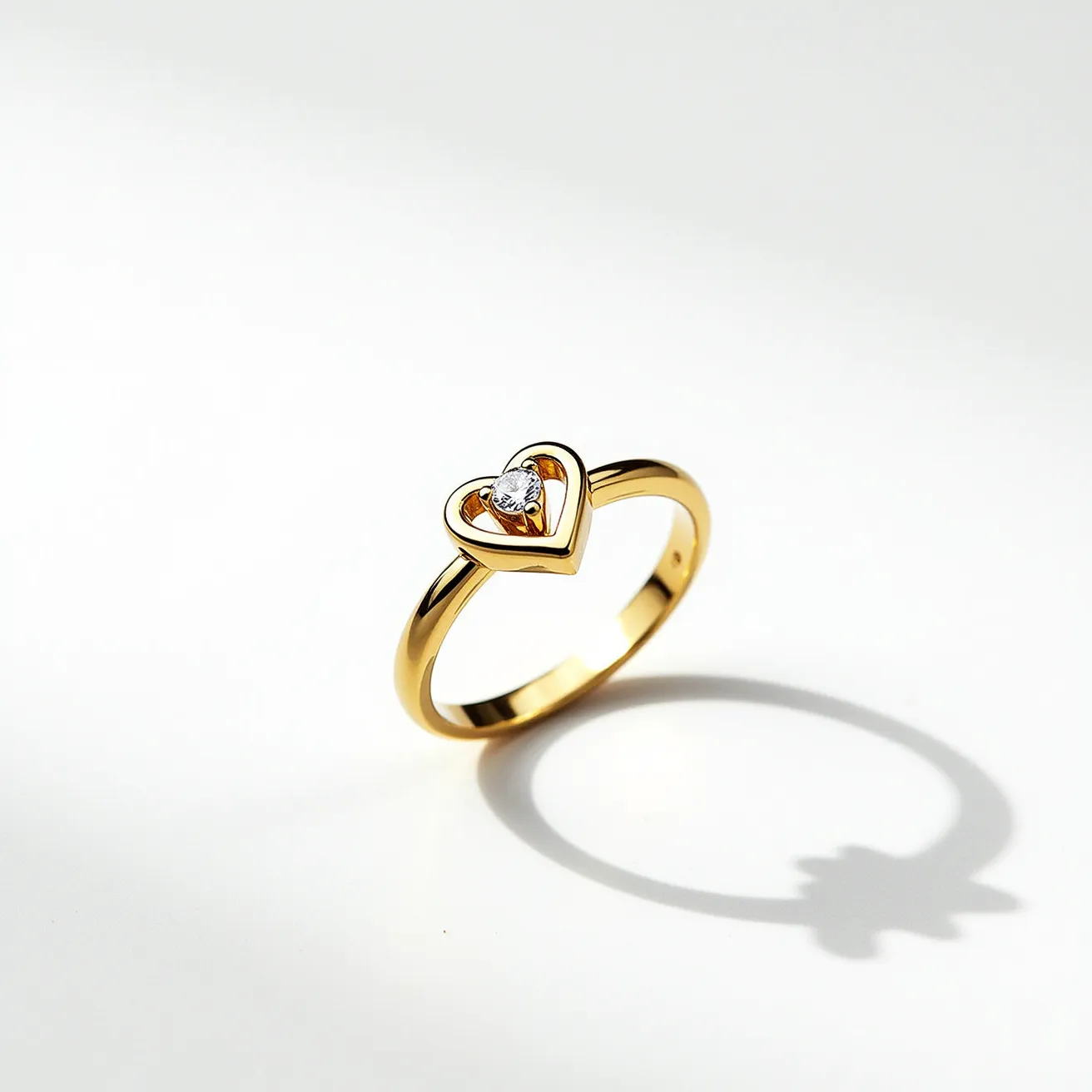 This heart ring is crafted from a gold-toned metal, featuring a charming heart-shaped design at the center. Within the heart frame, a single round-cut gemstone is set, possibly a diamond or a similar transparent gem, which is securely nestled in a prong setting. The ring exhibits a smooth, polished finish, adding elegance and a touch of sophistication to the overall look. There are no visible clasps or attachments, as it is designed as a typical finger ring.