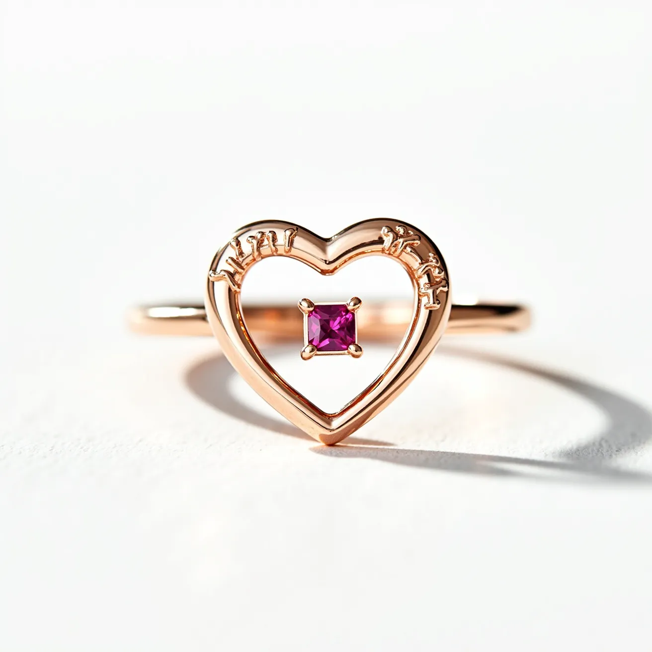 This heart ring features a delicate open-heart design crafted from rose gold, giving it a warm and elegant appearance. At the center of the heart is a square-cut pink gemstone, securely held in place by a four-prong setting that enhances its visual appeal. The ring's band smoothly integrates with the heart, ensuring a seamless and cohesive design. The small, intricate engravings around the top of the heart add a subtle yet sophisticated touch, contributing to the overall charm and uniqueness of the piece.