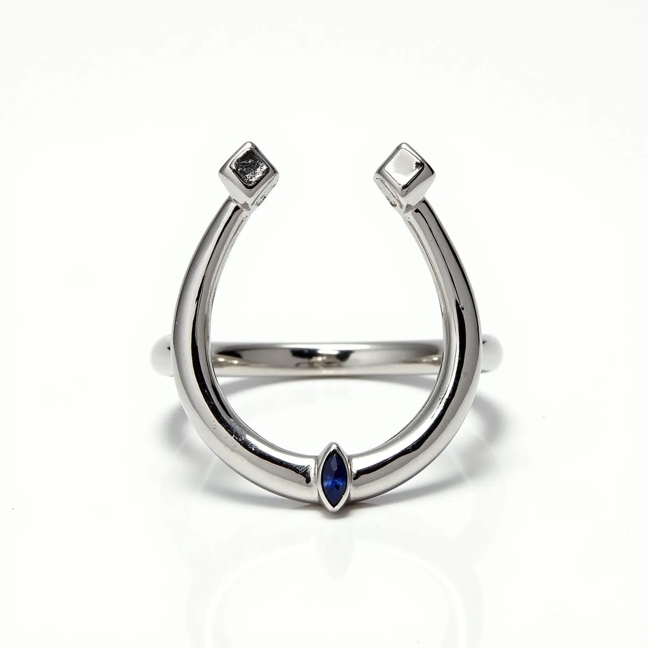 This horseshoe ring features a sleek, metallic band that elegantly curves into the iconic horseshoe shape. At the base of the horseshoe, there is a marquise-cut blue gemstone, likely a sapphire, set securely within the metal. The ends of the horseshoe are capped with small, square-shaped settings that add a distinctive geometric touch. The polished finish of the metal enhances the overall sophisticated and modern look of the ring.