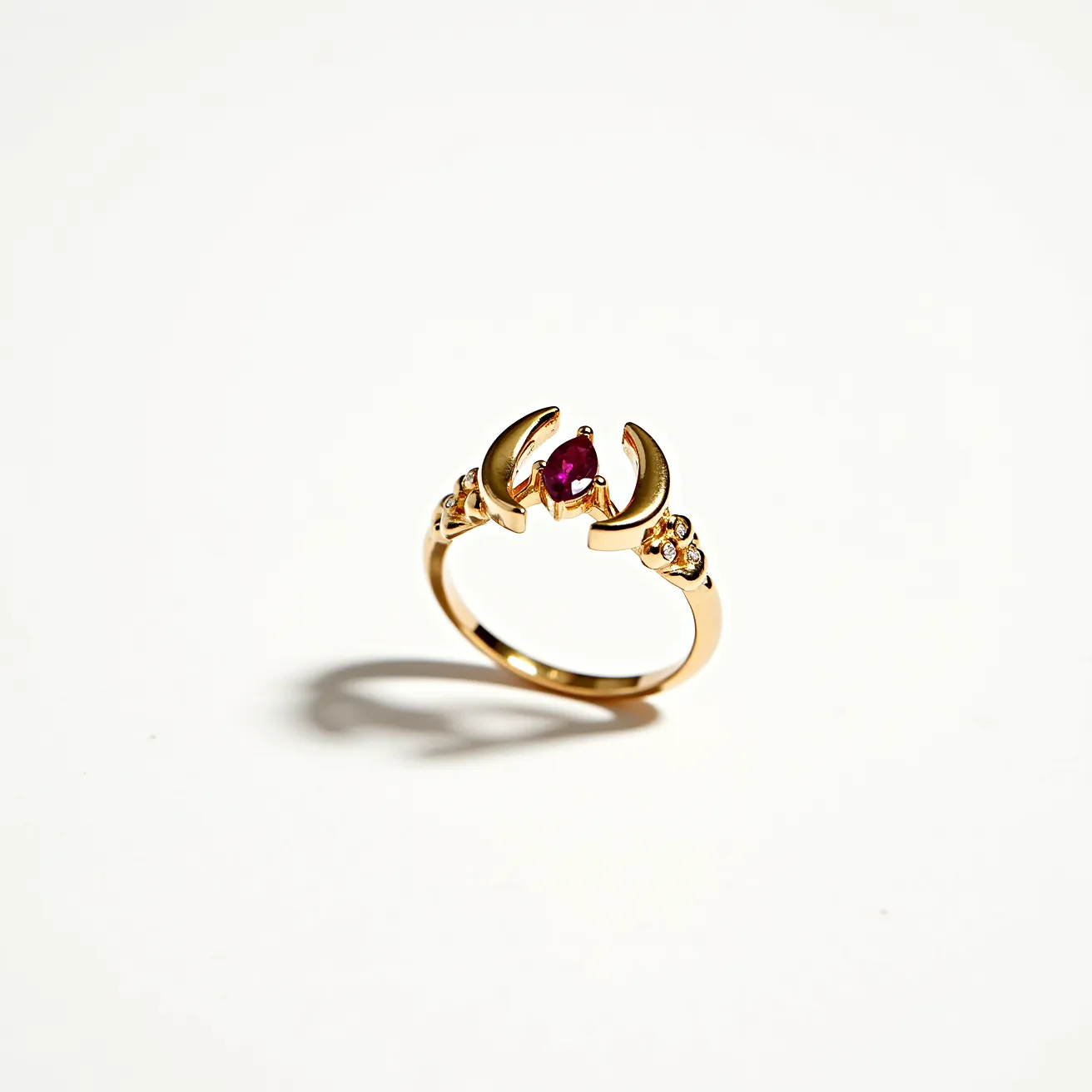 This horseshoe ring features a gold band with a distinctive horseshoe design at its center. In the middle of the horseshoe is a marquise-cut red gemstone, likely a ruby, securely held in place by a prong setting. On either side of the central gem, there are small decorative motifs that resemble clusters of tiny round diamonds, each intricately set into the gold band. The ring’s overall design blends elegance with a touch of symbolic charm, highlighted by the contrasting colors of the deep red stone and the gleaming gold material.