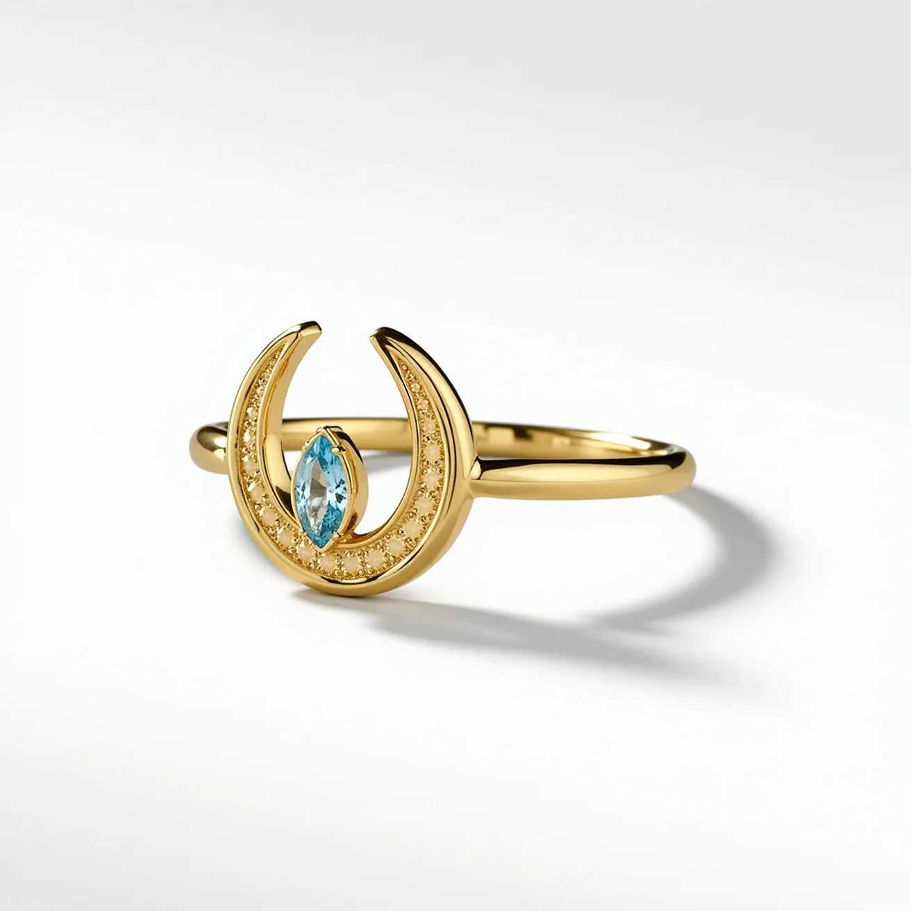 This horseshoe ring features a polished gold band with a prominent horseshoe-shaped design at its center. The horseshoe is adorned with a row of small, circular inset gems that enhance its elegant look. In the middle of the horseshoe rests a marquise-cut blue stone, securely set in a prong setting, drawing attention to its vibrant hue and refined cut. The overall design is seamless, with no visible clasps or attachments, presenting a smooth and refined piece of jewelry.