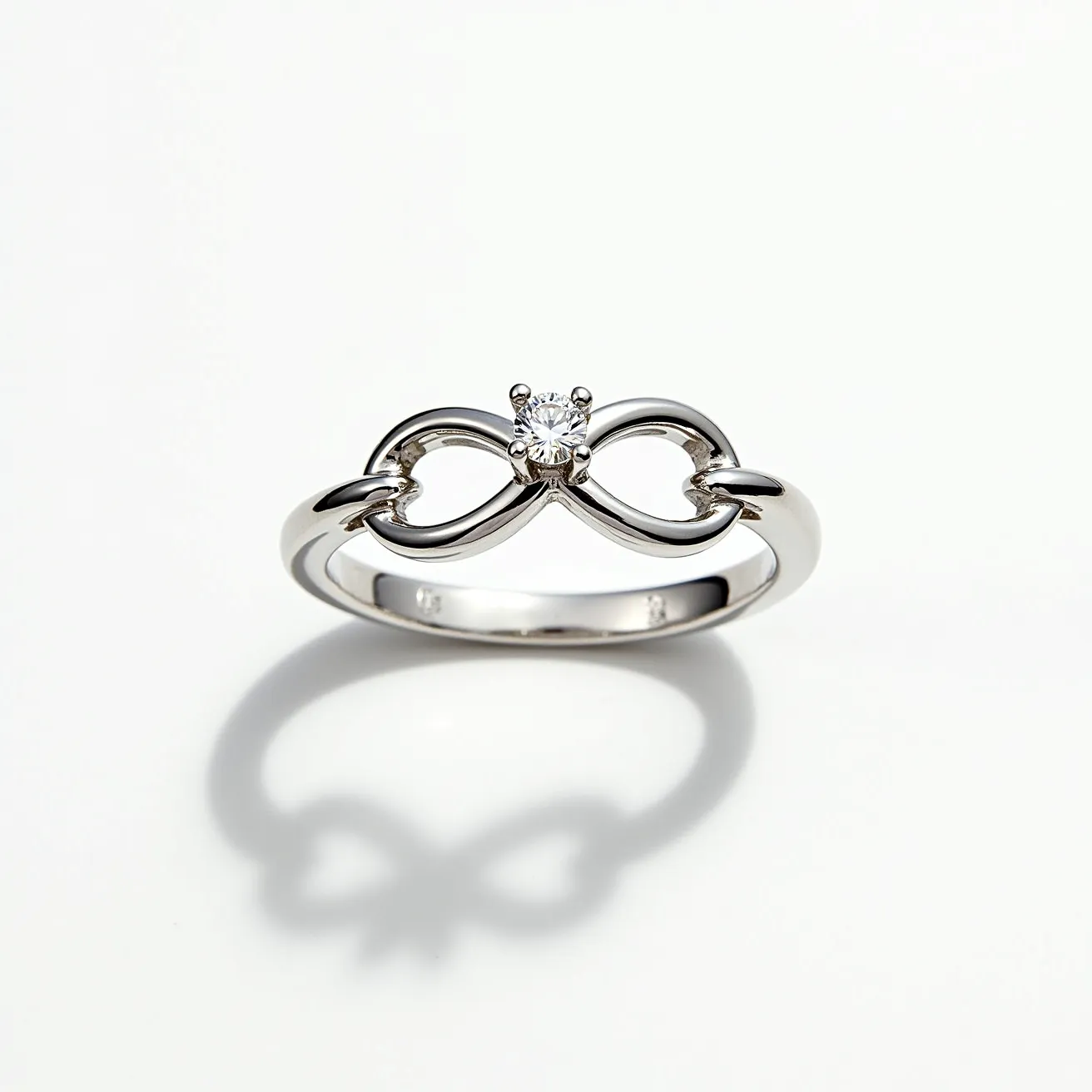 This infinity ring features a polished silver band forming an elegant infinity loop at the center. Set at the heart of the infinity symbol is a sparkling round-cut diamond, securely held in place by four prongs for maximum brilliance. The prong setting elevates the diamond slightly above the band, allowing light to enhance its shine. The seamless design of the band provides a continuous and smooth appearance, embodying the idea of eternal and unending beauty.