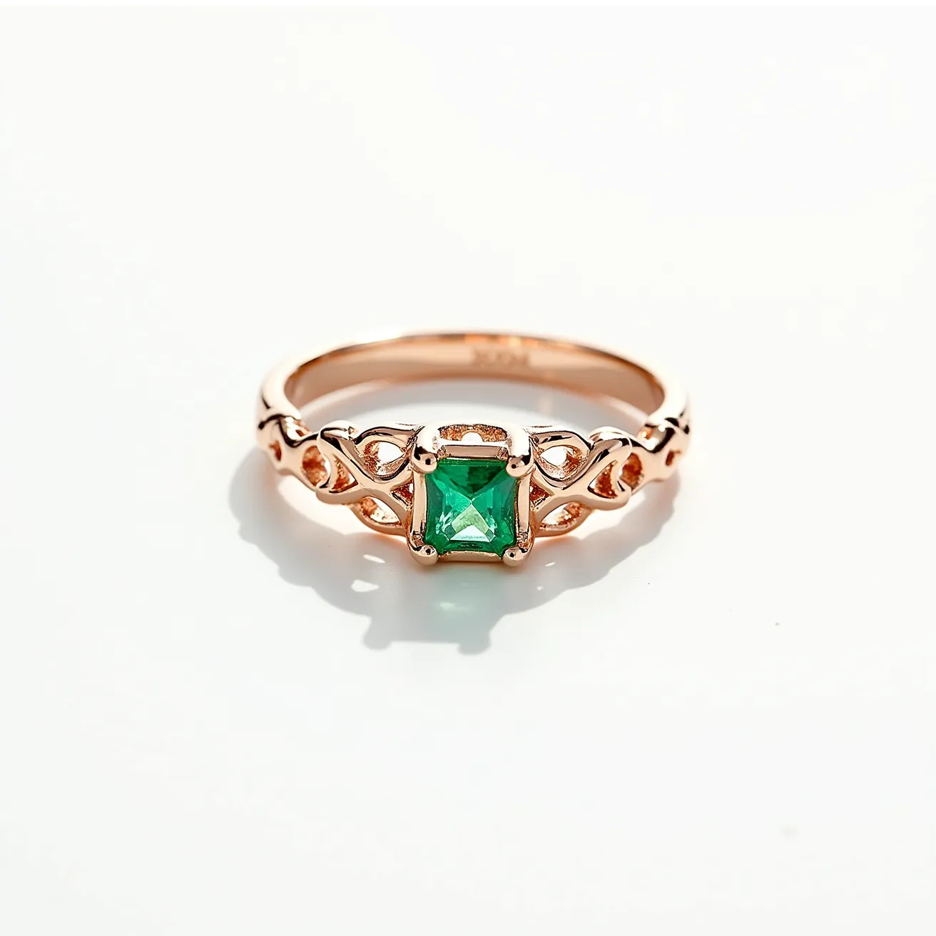 This Irish promise ring features a beautifully ornate design crafted from a rose gold metal, which lends a warm and elegant tone. The centerpiece is a vibrant emerald-cut green gemstone, securely held in a prong setting that highlights its square shape and enhanced sparkle. The band is intricately detailed with Celtic-inspired motifs, showcasing an elegant interlaced pattern that adds to the ring’s symbolic and traditional significance. The overall composition offers a blend of classic Irish craftsmanship and contemporary elegance.