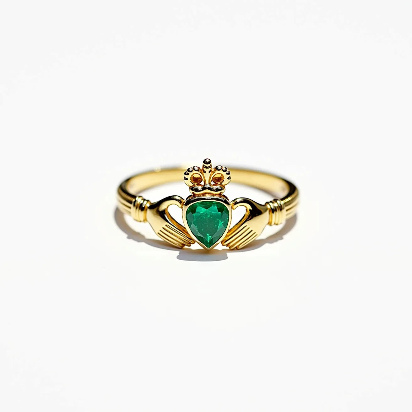 This Irish promise ring features a classic Claddagh design crafted from gold, showcasing two hands holding a heart topped with a crown. At the center of the heart, there's a pear-cut green gemstone, likely an emerald, securely set to enhance its deep color and sparkle. The band is elegantly shaped and smooth, seamlessly integrating the hands which gently cradle the heart, symbolizing love, loyalty, and friendship. The crown adds a regal touch, completing the traditional symbolism of the piece. The overall design is both intricate and meaningful, embodying the rich heritage of Irish craftsmanship.