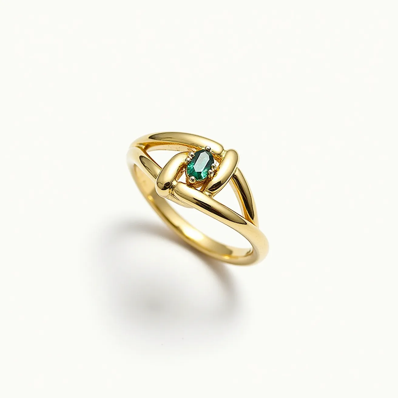 This knot ring features a polished gold band elegantly forming a knot design at its center. It is adorned with a small, marquise-cut green gemstone, likely an emerald, set in a secure prong setting that highlights the stone's vibrant color. The smooth and shiny texture of the gold enhances the overall sophistication and timelessness of the piece. The minimalistic design ensures that the knot and gemstone remain the focal points of this delicate and stylish ring.