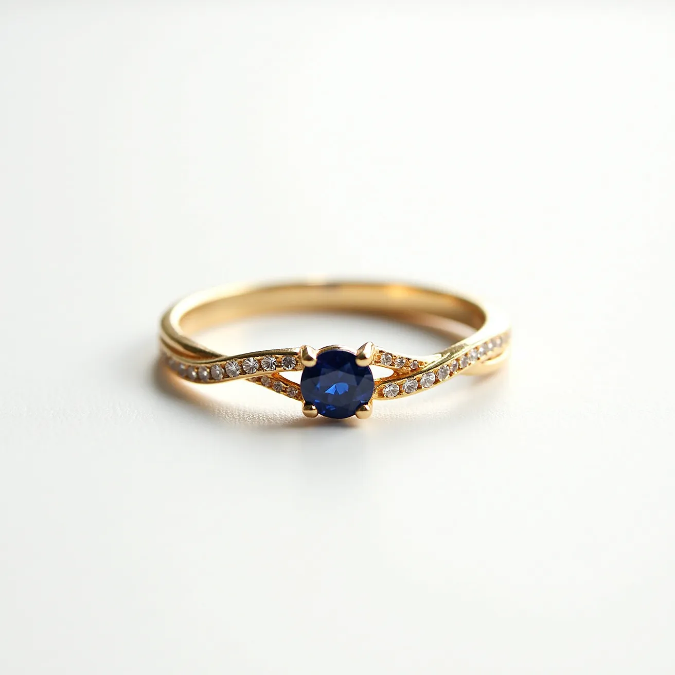 This knot ring showcases a graceful design with a gold band that elegantly twists together, creating an intricate knot effect. The band is adorned with small, round-cut diamonds, set in a delicate pave style that accentuates the shimmer of the piece. At the center, a stunning round-cut blue sapphire, held securely in a four-prong setting, serves as the focal point of the ring. The combination of gold, diamonds, and a central sapphire lends the ring a classic and luxurious appeal.