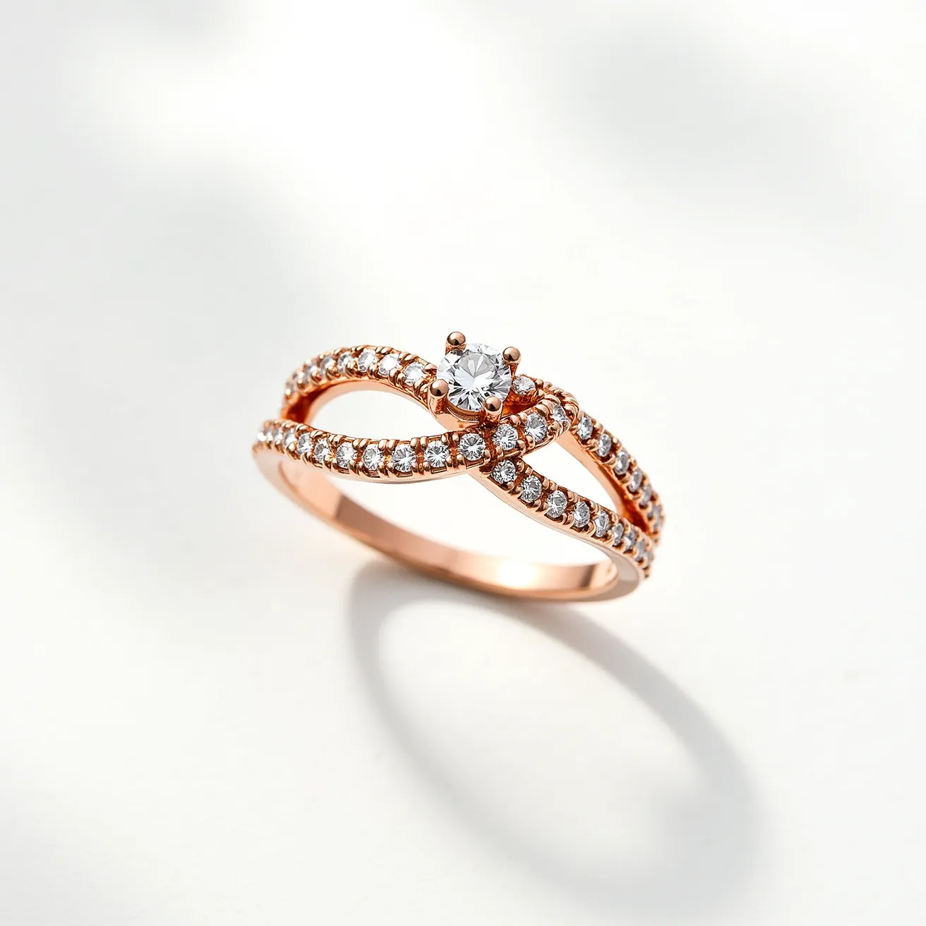 This knot ring features a sophisticated design crafted from a rose gold band, which elegantly weaves into a knot at the center. The ring showcases a series of small, round-cut diamonds, intricately set along the intertwining bands in a pavé setting, adding an exquisite sparkle. At the center of the knot, a larger, round-cut diamond is prominently displayed, held securely in place by a classic four-prong setting. The combination of the rose gold with the brilliance of the diamonds creates a harmonious and luxurious appearance, emphasizing both elegance and modernity.