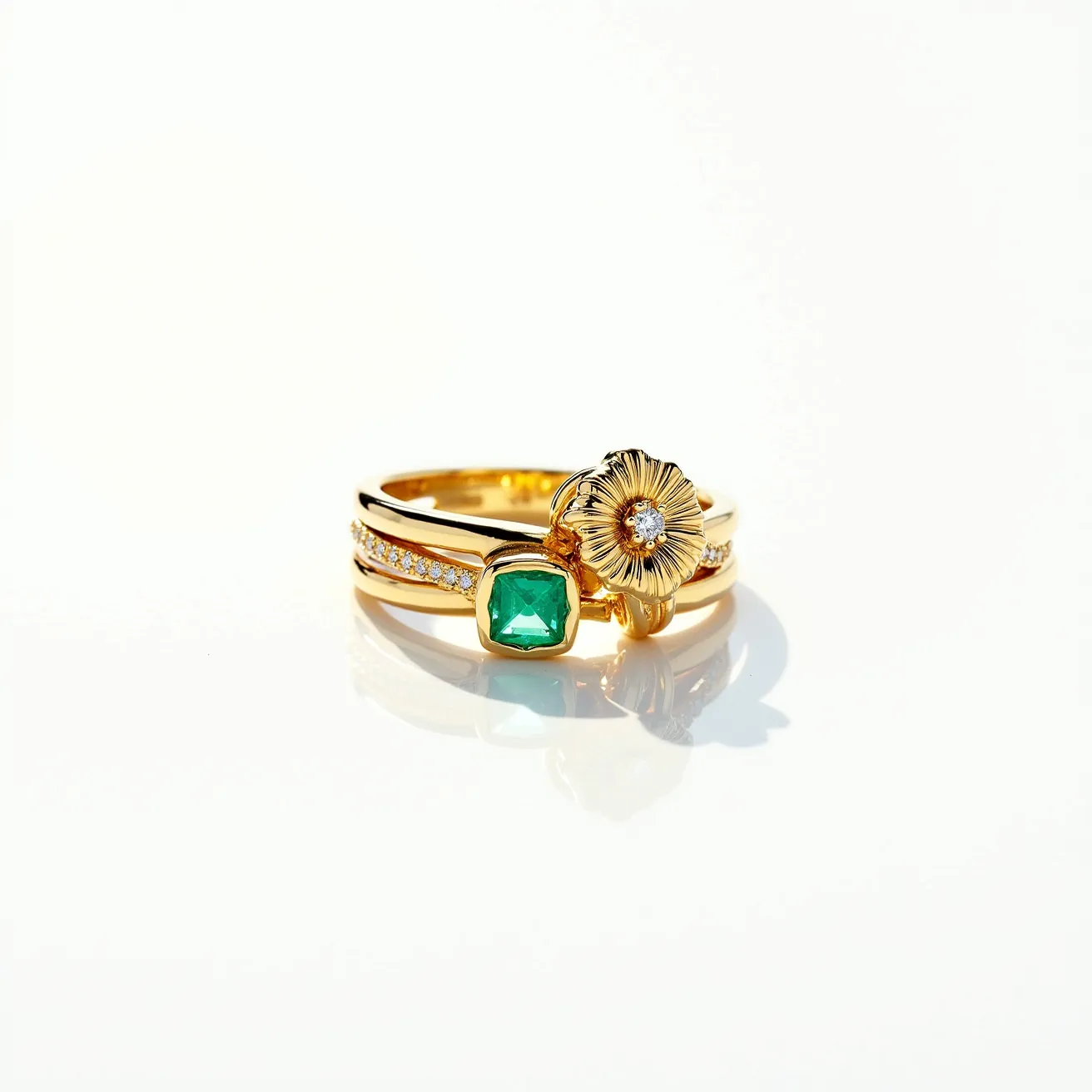 This knot ring features a delicately intertwined design crafted from gold, showcasing a sophisticated and timeless elegance. The band incorporates two distinctive adornments: a vibrant green stone, cut in a cushion shape and set securely in a bezel setting, and a floral motif with intricate petal detailing surrounding a small, central diamond, set in a prong setting. The band is further embellished with a line of small, sparkling diamonds embedded into the metal, adding an extra layer of brilliance. The combination of vivid green and clear stones against the warm gold creates a striking visual contrast, enhancing the overall aesthetic appeal of the ring.