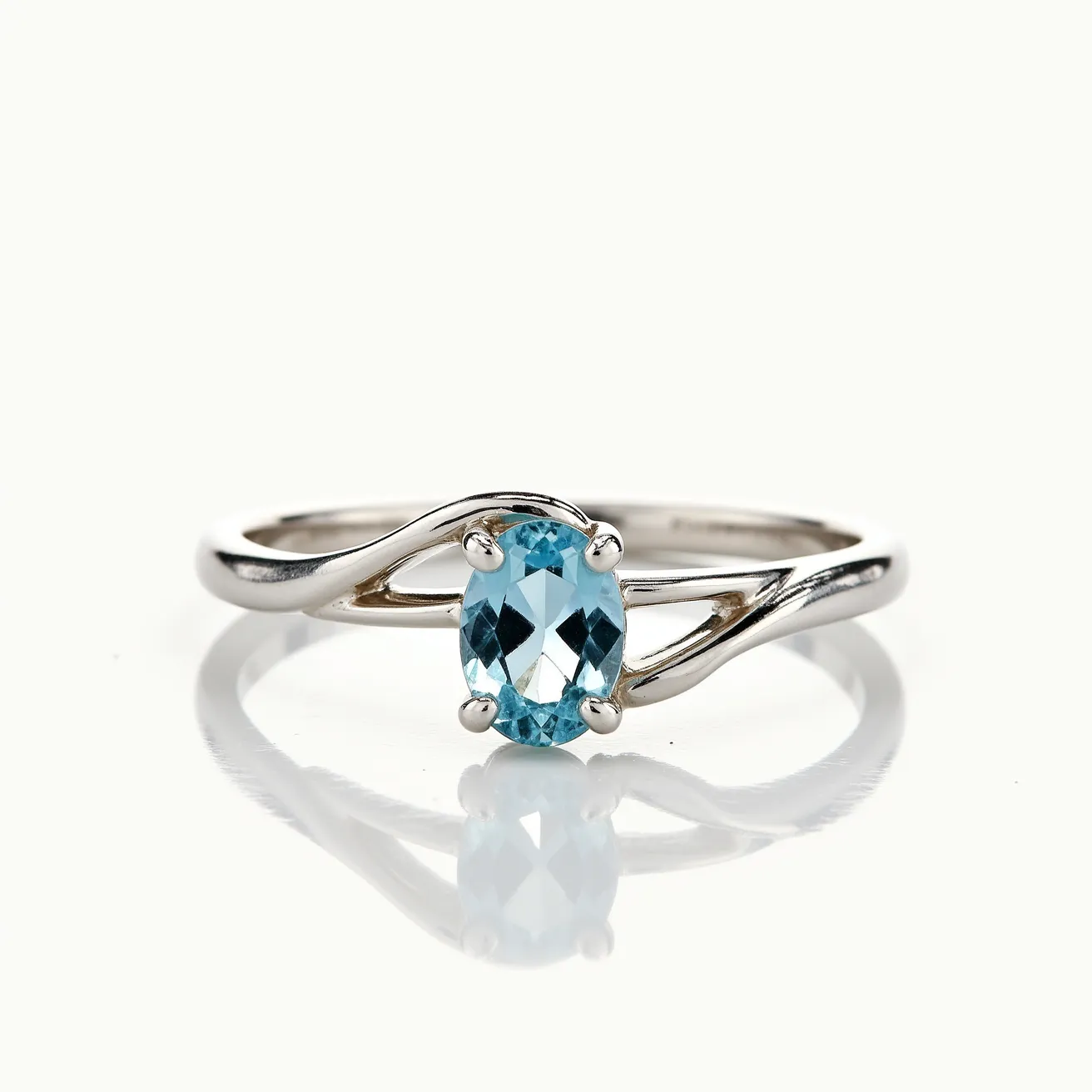 This March birthstone ring features a delicate aquamarine gemstone, which is set in an elegant prong setting. The aquamarine, cut in an oval shape, exhibits a serene, light blue hue that is emblematic of March's birthstone. The ring's band appears to be crafted from polished white gold or sterling silver, adding a sleek and modern touch to the overall design. The band gracefully twists around the aquamarine, highlighting its beauty and ensuring it takes center stage. This elegant piece combines the calming essence of aquamarine with a refined metal band to create a sophisticated and timeless accessory.