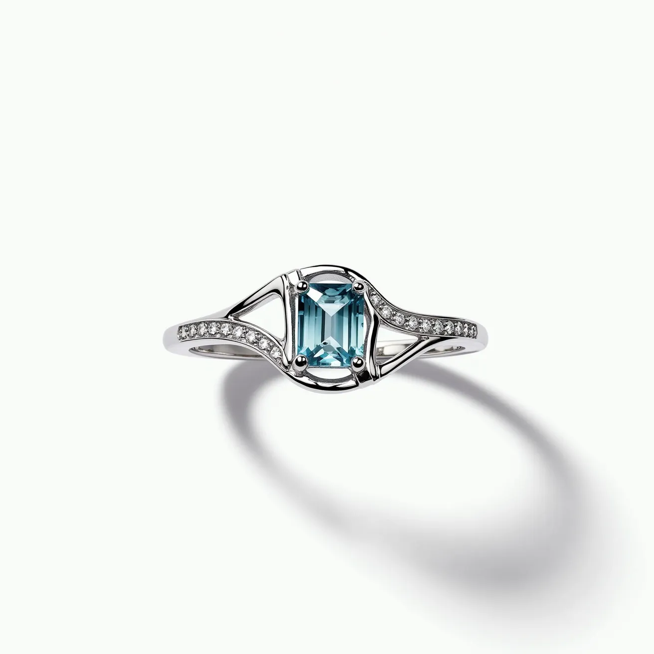 This March birthstone ring features an elegantly cut aquamarine gemstone, showcased in an emerald cut that beautifully enhances its clarity and color. The aquamarine is set in a secure four-prong setting, which ensures its stability while adding to its allure. Surrounding the central gemstone, the band is adorned with a series of small, round-cut diamonds set into the metal, providing a sparkling contrast to the vibrant aquamarine. The band itself is crafted from polished white gold, offering a sleek and sophisticated appearance that complements the stones. The overall design of the ring is both contemporary and classic, making it a timeless piece of jewelry.