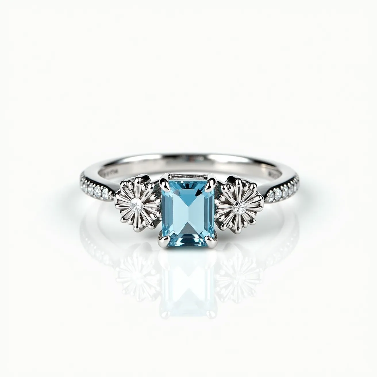 This March birthstone ring features a striking aquamarine gemstone, known for its serene blue hue, cut into an elegant rectangular shape and secured by a polished four-prong setting. The band showcases intricate floral designs on either side of the central stone, adding an artistic touch. Accompanying the aquamarine are small, sparkling accent diamonds set along the ring’s shank, enhancing its overall shimmer. The metal appears to be a lustrous silver or white gold, providing a sleek and sophisticated backdrop for the gems. This exquisite combination of materials and design elements embodies both elegance and craftsmanship.