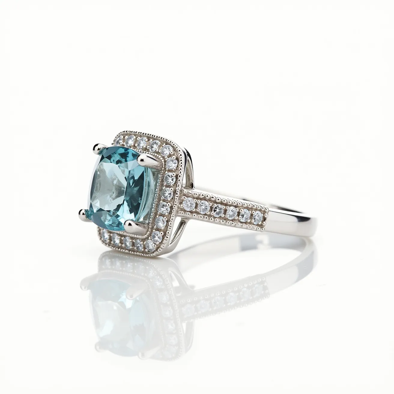 This March birthstone ring features a stunning aquamarine gemstone, which exhibits a delicate blue hue, beautifully cut in a cushion shape. The aquamarine is set in a four-prong setting, ensuring that the stone is securely held while enhancing its natural brilliance. Surrounding the central gem is a halo of smaller round white diamonds, which add an exquisite sparkle to the piece. The diamonds continue along the shoulders of the ring, providing a seamless flow of elegance. The band itself appears to be crafted from a lustrous white metal, likely white gold or platinum, which complements the cool tones of the aquamarine and diamonds.