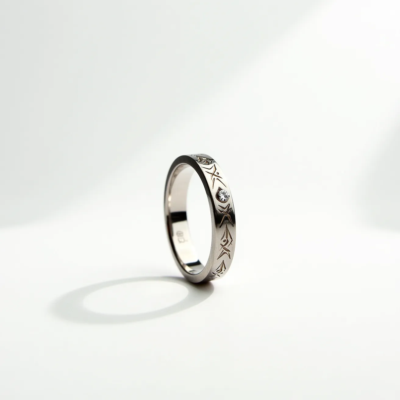 This men's pinky ring is crafted from a lustrous metal, likely silver or white gold, reflecting a sleek and polished finish. It features a series of intricate, engraved geometric patterns encircling the band, adding an element of sophistication and style. The ring is set with a small, round-cut diamond or diamond-like gemstone, providing a subtle yet eye-catching sparkle. The stone is bezel-set, ensuring a secure and integrated appearance within the design. Overall, the ring combines elegance with a modern touch, making it a versatile accessory for various occasions.