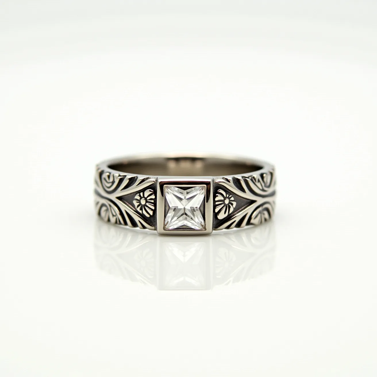 This men's ring features an intricate design crafted from silver-toned metal, showcasing ornate patterns along the band. At its center, the ring is adorned with a square-cut clear gemstone, securely set in a bezel setting that highlights its geometric shape. The band's decorative elements add a sophisticated touch, enhancing the stone's brilliance. Overall, the ring's combination of detailed metalwork and a prominent gemstone creates a striking piece of jewelry.