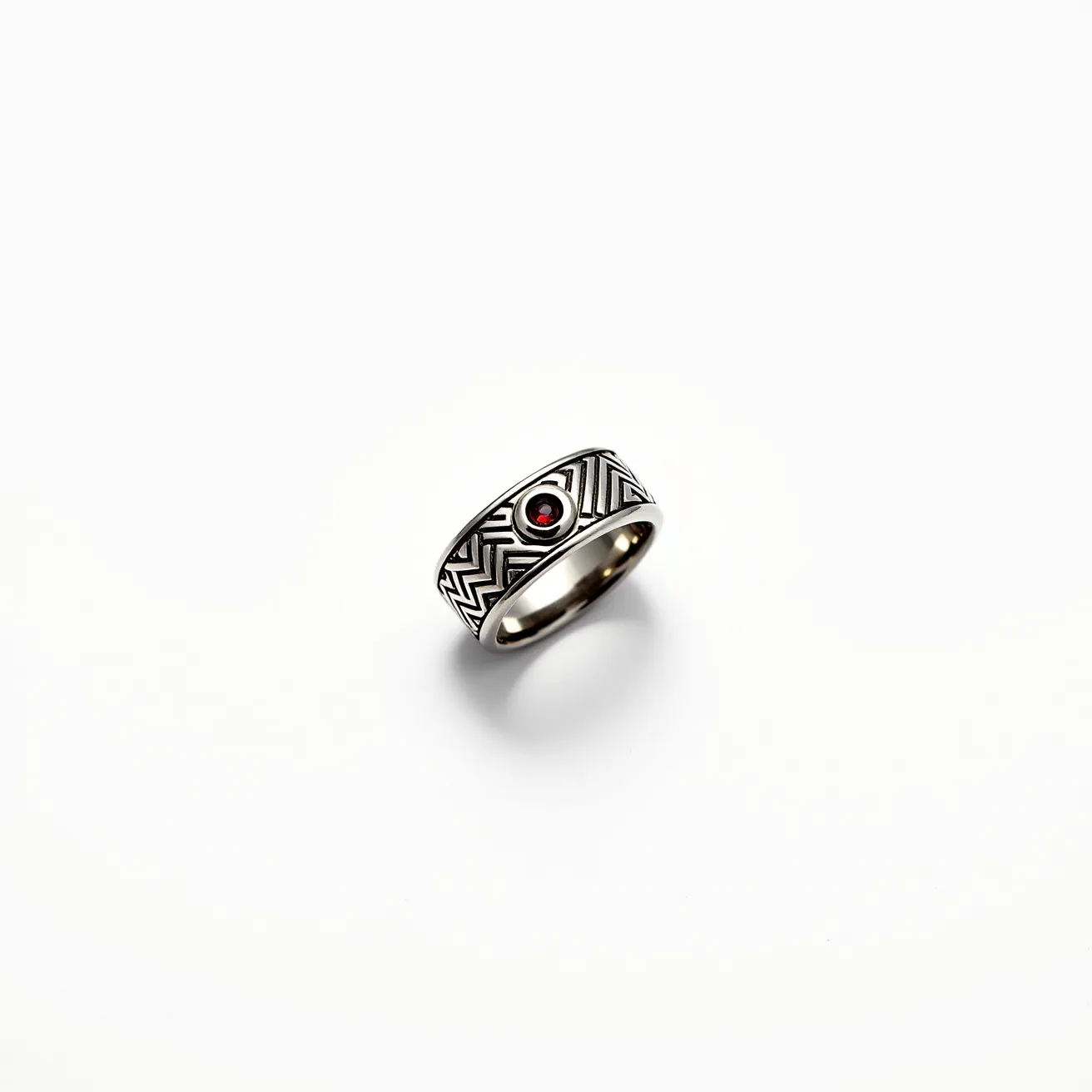 This men's ring showcases a bold and intricate design made from a silvery metal, adorned with a striking geometric pattern that encircles the band. At its center, the ring features a round, deep red gemstone, possibly a garnet, set into the metal with a bezel setting that secures the stone while allowing its color to stand out vividly. The contrast between the metal's sheen and the rich hue of the gemstone adds a sophisticated touch, making it an eye-catching piece. The ring does not appear to have any clasps or additional attachments, maintaining a seamless, circular form.