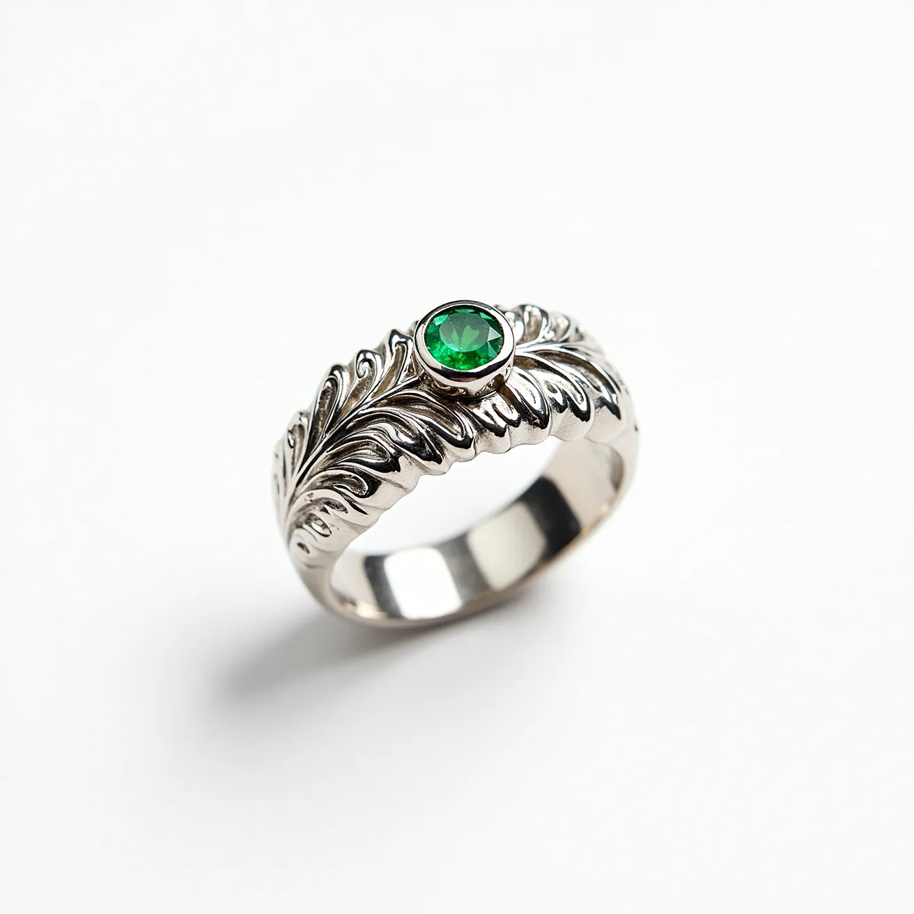 This men's silver ring features an intricate leaf pattern, beautifully showcasing craftsmanship in its design. At the center, it holds a round-cut green gemstone, set securely within a bezel setting. The use of silver as the primary material gives the ring a polished and sleek appearance, enhancing the vibrant hue of the stone. The stone's secure bezel setting ensures durability and complements the overall elegant aesthetic of the piece, making it a striking accessory.