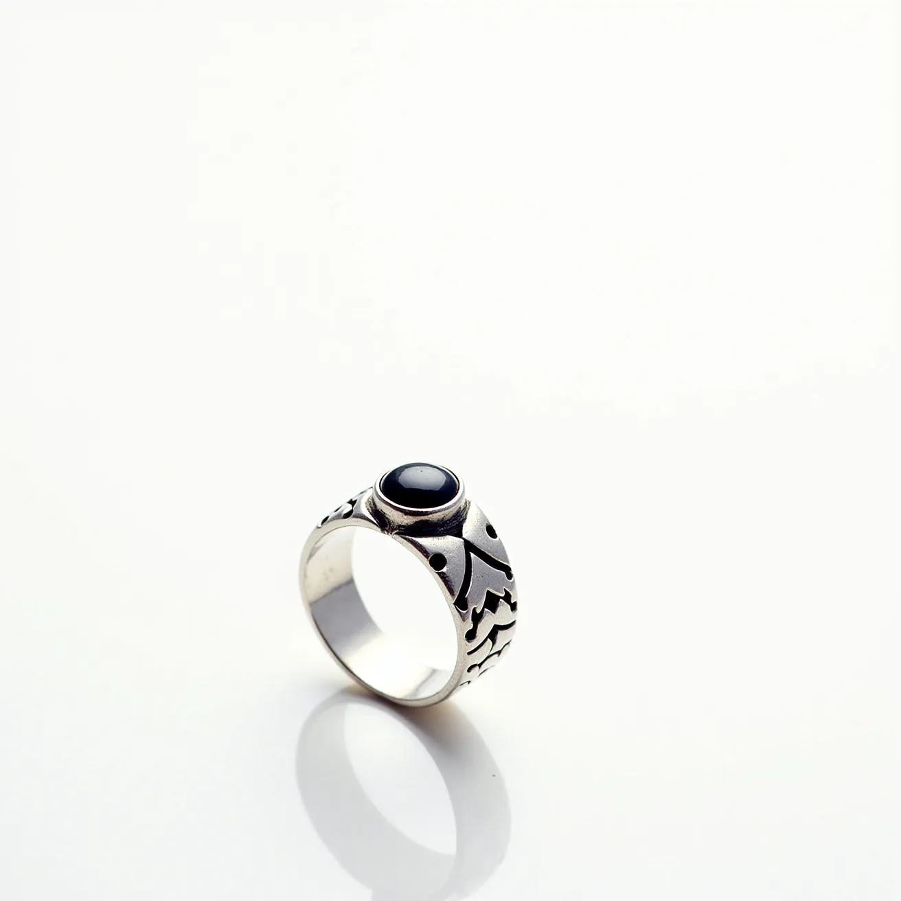 This men's silver ring features a bold design with intricate carvings along the band, which are both decorative and eye-catching. The focal point of the ring is a dark stone, likely onyx, set in a smooth bezel setting, which securely holds the stone in place while emphasizing its polished finish. The silver material lends a sleek and modern look to the piece, harmonizing with the stone's deep hue. There are no additional clasps or attachments, allowing the ring to maintain a seamless and classic appearance.