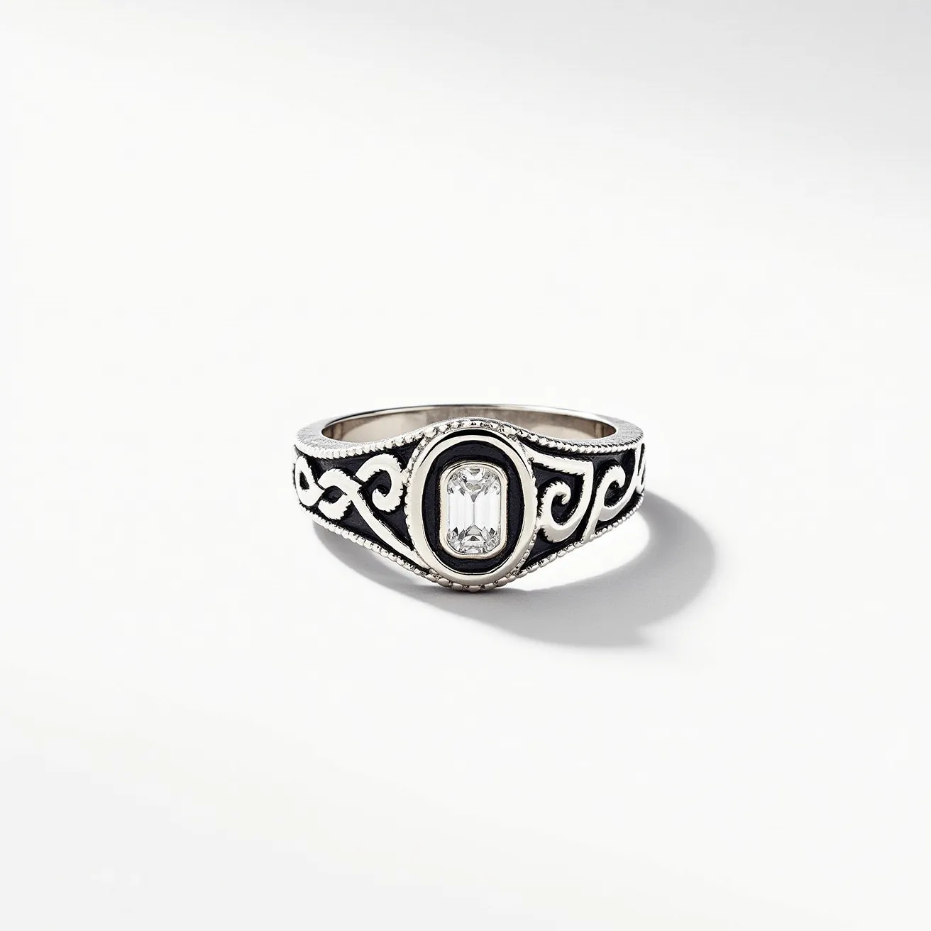 This men's silver ring features intricate scrollwork designs across the band, adding an elegant and classic touch. At the center, it showcases an emerald-cut clear gemstone, set within an oval bezel that highlights its sophisticated appeal. The gemstone's cut emphasizes clarity and brilliance, making it a striking centerpiece. The silver band is polished and smoothly transitions into the setting, ensuring comfort while maintaining a robust and stylish appearance. The artistry in the design is complemented by the choice of materials, embodying both refinement and durability.