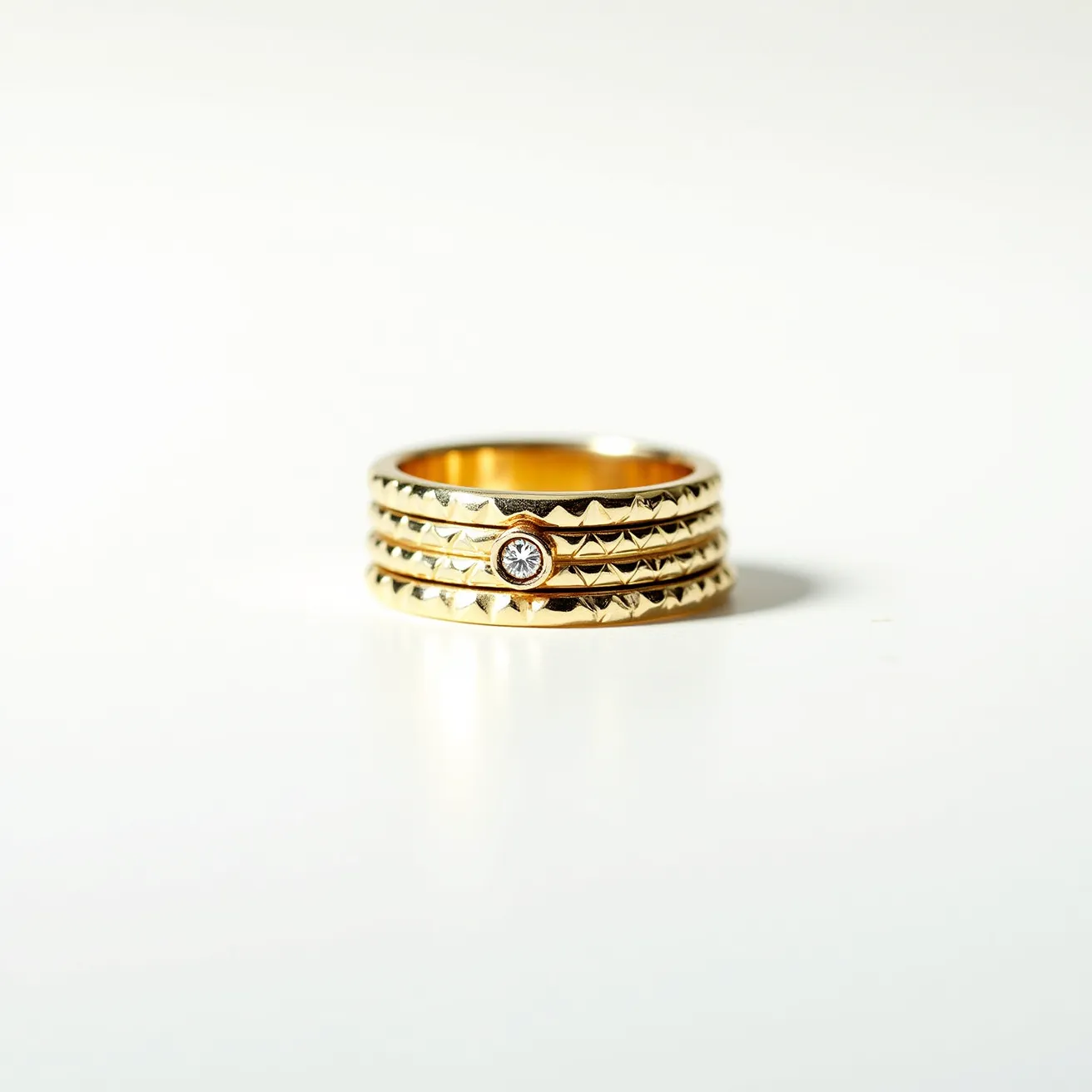 This men's spinner ring features a lustrous gold-tone finish with intricate detailing that includes a series of geometric patterns encircling the band. The design incorporates a small, centrally set gem that appears to be a round-cut diamond, held securely in a bezel setting that provides both durability and style. The ring's construction highlights its sleek and sophisticated form, with the inner band designed to spin independently, offering a tactile and engaging experience. The overall aesthetic is one of elegance and modernity, with a focus on both form and function.