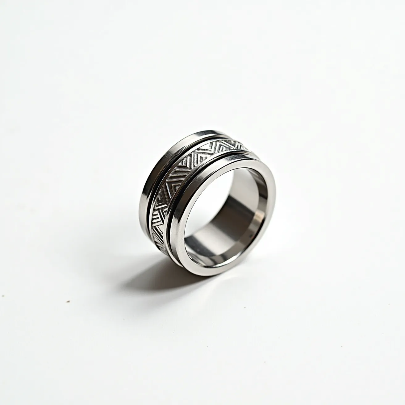 This mens spinner ring features a sleek and polished design crafted from stainless steel. It includes a central band that rotates freely around the inner ring, adorned with an intricate geometric pattern. The pattern includes repeating triangular motifs that add texture and visual interest to the piece, enhancing its modern aesthetic. This ring does not feature any gems, stones, or clasps, relying purely on the precision of its material and design to provide a sophisticated accent for everyday wear.