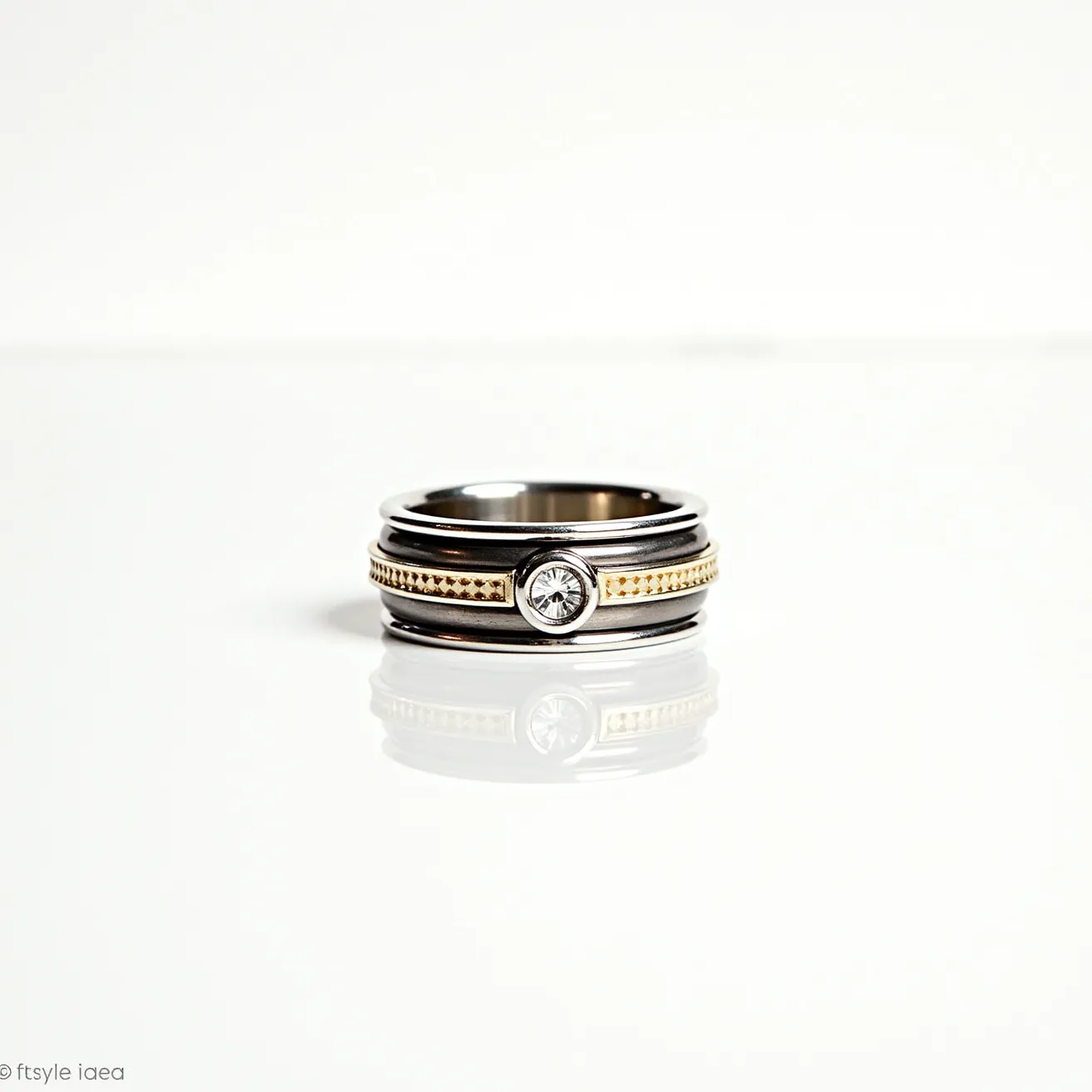 This men's spinner ring is crafted with a blend of sleek stainless steel and gold-toned accents. The design features a central band with a textured, beaded gold pattern that provides a striking contrast to the polished silver hues of the steel. At the center of the ring, a single round-cut stone is set securely in a bezel setting, adding an elegant touch. The ring lacks any additional clasps or attachments, relying on its substantial design and materials for style and durability.