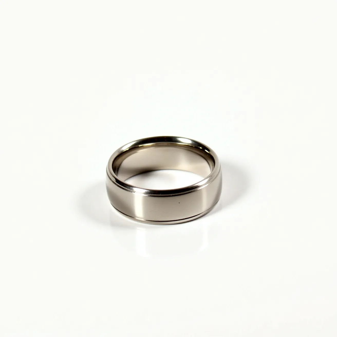 This men's wedding band showcases a sleek, polished appearance crafted from a durable silver-toned metal, possibly tungsten or titanium, known for its strength and resistance to scratches. The band features a classic domed shape with a smooth, reflective surface that enhances its modern elegance. It is designed without any gemstones, offering a minimalist aesthetic. The band is a continuous circle, typical of wedding rings, which indicates a solid construction without any clasps or attachments, ensuring a secure and comfortable fit.