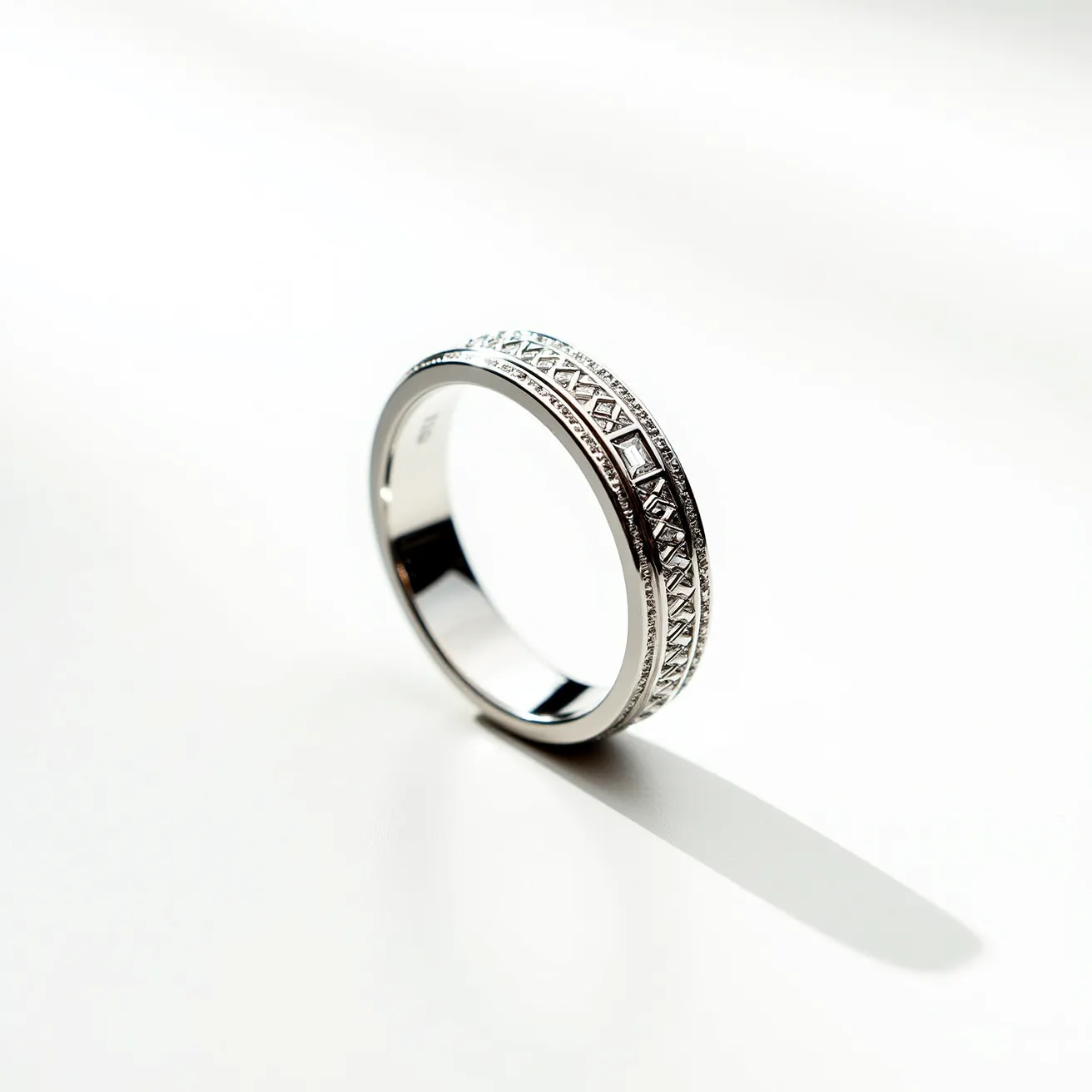 This men's wedding band features a sleek, polished material, likely crafted from a high-quality metal such as platinum or white gold. It showcases an intricate pattern along its outer surface, providing a textured and visually appealing design. The band may incorporate small, subtle stones set within the pattern, adding a touch of elegance and sparkle, although their specific type or cut is not immediately discernible. The overall design is seamless, with no visible clasps or attachments, emphasizing its continuous and enduring nature as a symbol of commitment.