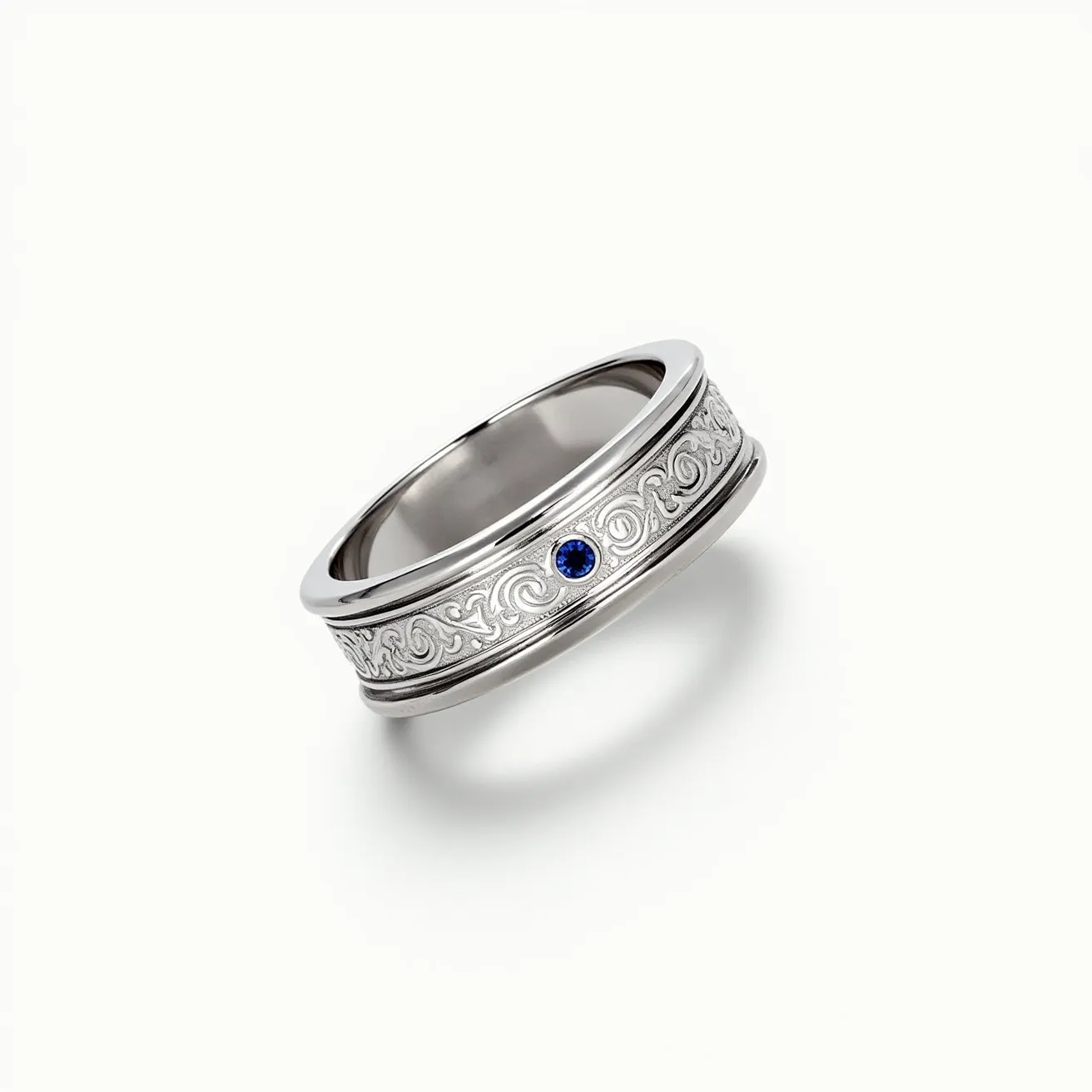 This men's wedding band features a sleek silver material, possibly platinum or white gold, with a detailed, engraved scrollwork design running along its outer surface. It is adorned with a single blue gemstone, likely a sapphire, set in a bezel mount that adds an elegant touch to the overall design. The band does not have any visible clasps or additional attachments, suggesting a seamless, continuous loop typical of traditional wedding bands.