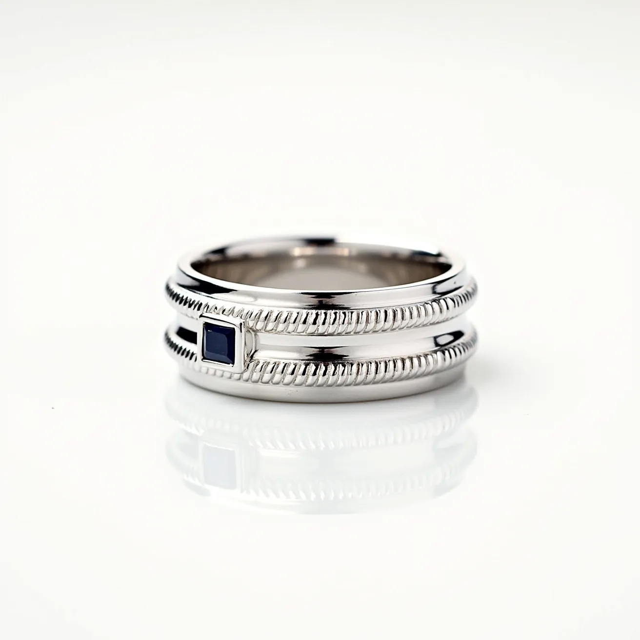 This men's wedding band features a sleek and polished metal design, likely composed of platinum or white gold. It is embellished with a finely detailed rope-like pattern running along its edges, adding texture and visual interest. The band is set with a single, square-cut blue sapphire, securely positioned in a bezel setting. The ring's construction is seamless, without any visible clasps or attachments, highlighting its sophisticated and classic aesthetic.