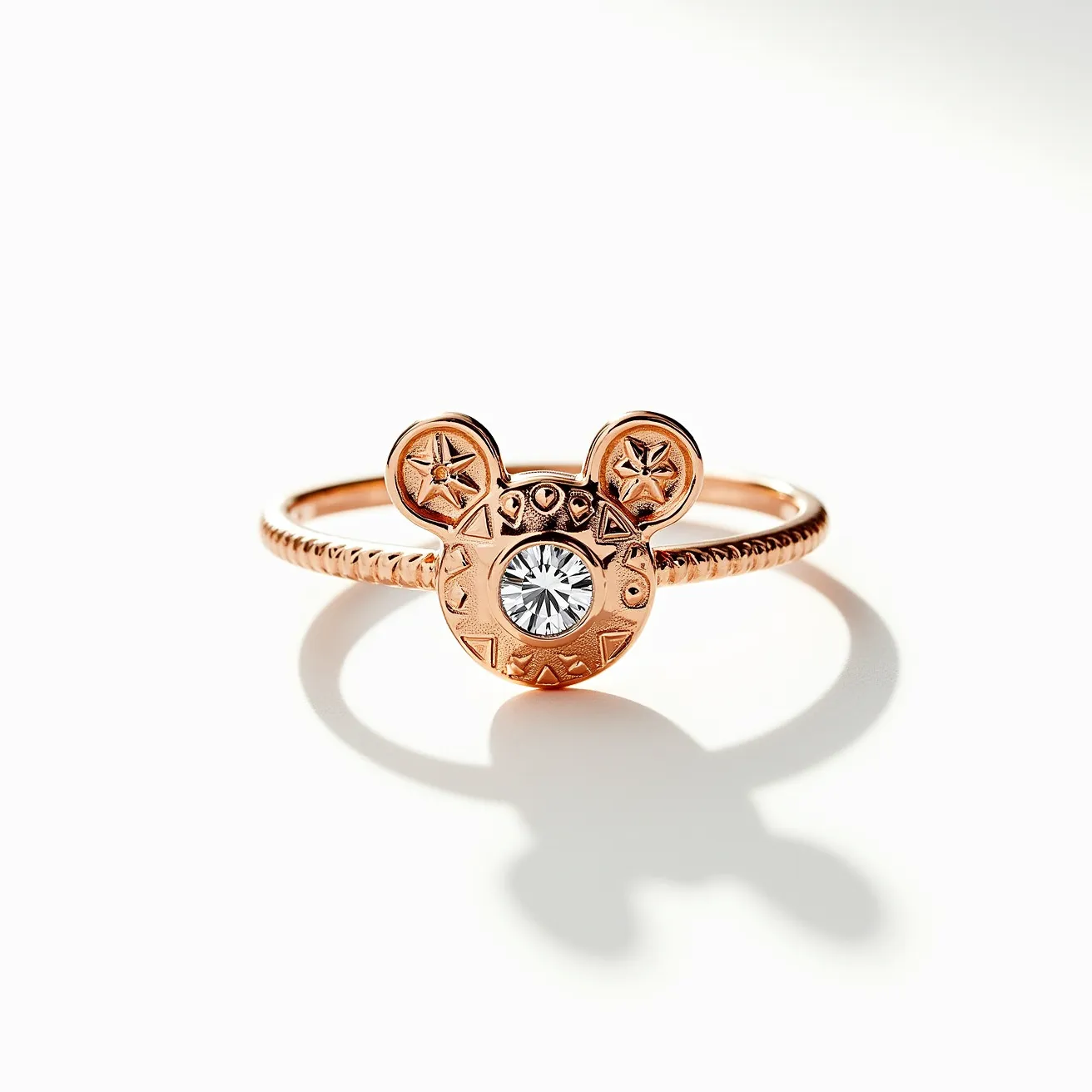 This Mickey Mouse ring features a rose gold band with a textured design, showcasing a distinctive Mickey Mouse head as the central motif. The head is embellished with a clear, round-cut gemstone set in the center, surrounded by engraved details that add to its charm. The gemstone is held in place with a bezel setting, ensuring security and a sleek appearance. The ears of the Mickey Mouse design also include star motifs, adding a playful touch. The ring does not appear to have any additional clasps or attachments, maintaining a simple, continuous band style.