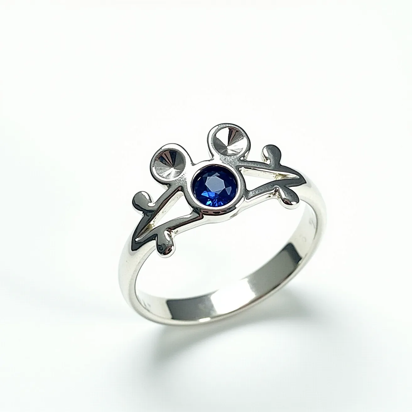 This Mickey Mouse ring features a sleek, shiny silver band, likely made of sterling silver or a similar metal. At the center is a round, blue gemstone, possibly a sapphire, which is elegantly set in a bezel setting. The gemstone represents the iconic silhouette of Mickey Mouse’s head, with two circular motifs flanking it to complete the shape. The design incorporates a playful yet sophisticated aesthetic, making it a charming piece for fans and collectors. The band is smooth and polished, providing a comfortable fit for the wearer.