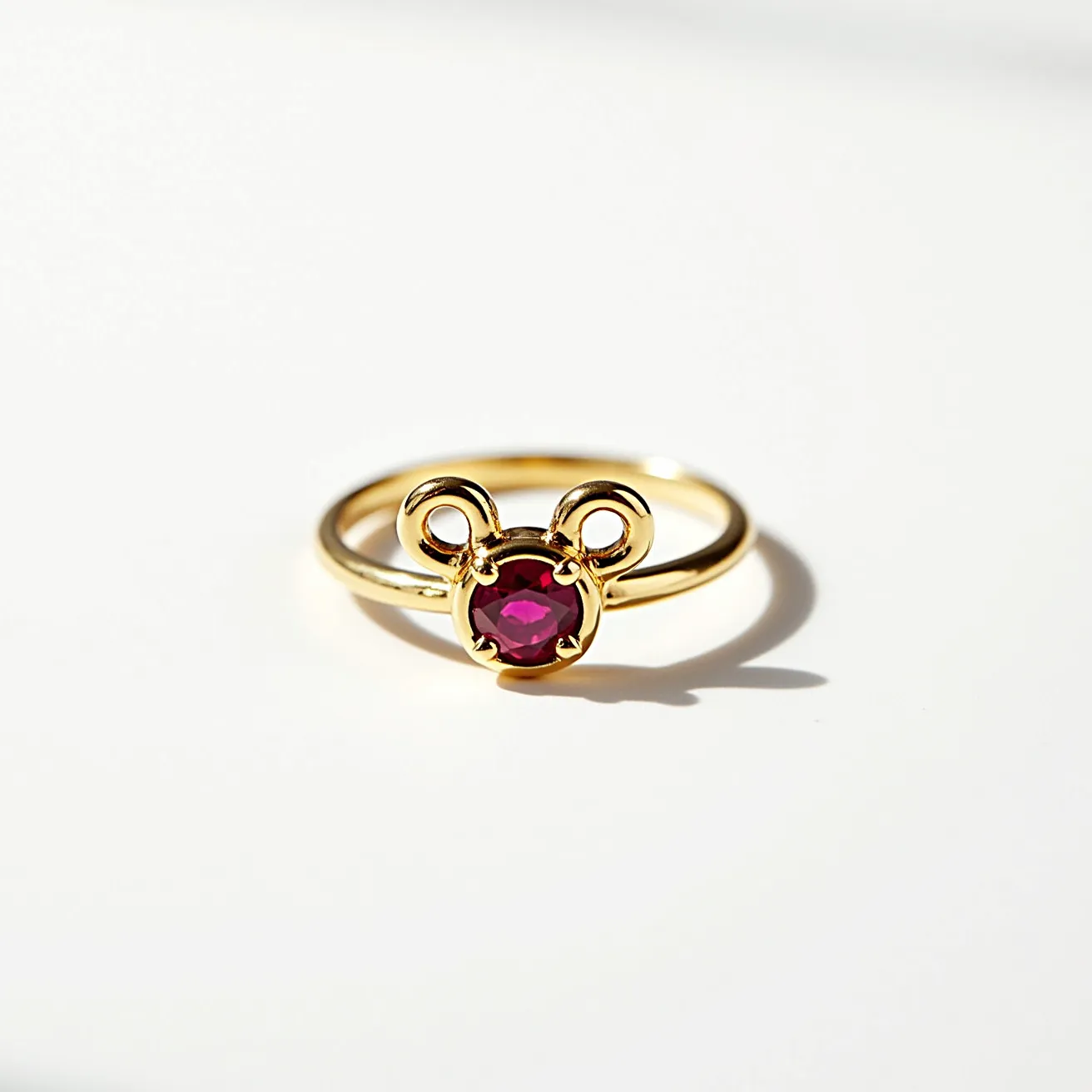 This Mickey Mouse ring features a gold band with a prominent design resembling Mickey's head. At its center, a round, faceted ruby-like gemstone is set, evoking a sense of playful elegance. The gemstone is secured in place with classic prongs, forming the face of the iconic character. Flanking the central gem are two gold loops that mimic Mickey’s ears, integrated seamlessly into the design, adding a whimsical touch to the piece. The simplicity of the band complements the intricate detailing of the centerpiece, making it a charming accessory for any Disney enthusiast.